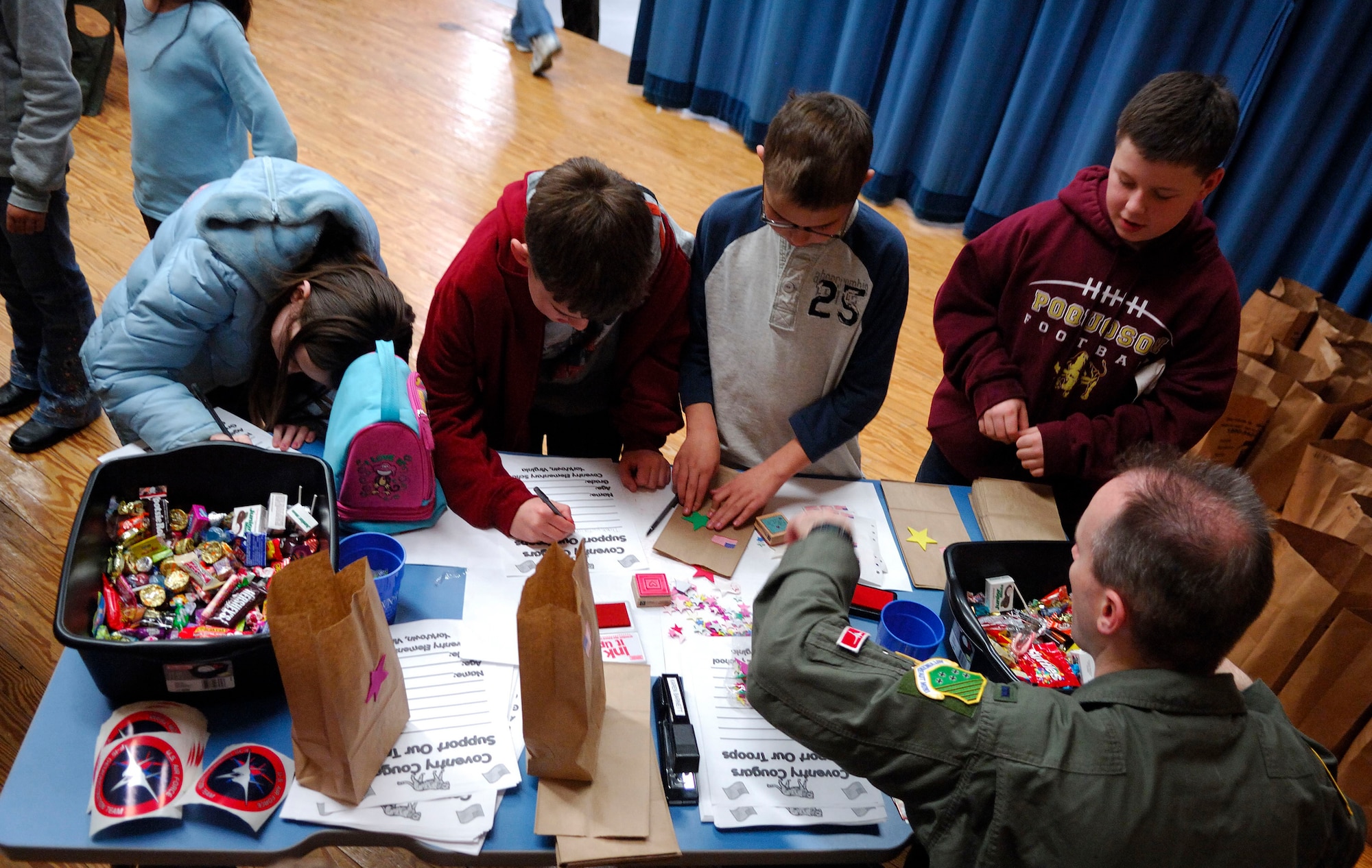 LANGLEY AIR FORCE BASE, Va. -- 1st Lt. Aaron Oliver, an F-15 Eagle pilot with the 71st Fighter Squadron, helps a group of Coventry Elementary School students in Yorktown, Va., decorate care bags Jan. 14 for soldiers in Iraq. The 71st FS and other military units on the peninsula have partnered with the school’s PTA and the United Service Organization to assist in implementing a program that helps children send messages of encouragement to soldiers in Iraq. (U.S. Air Force photo/Staff Sgt. Samuel Rogers)