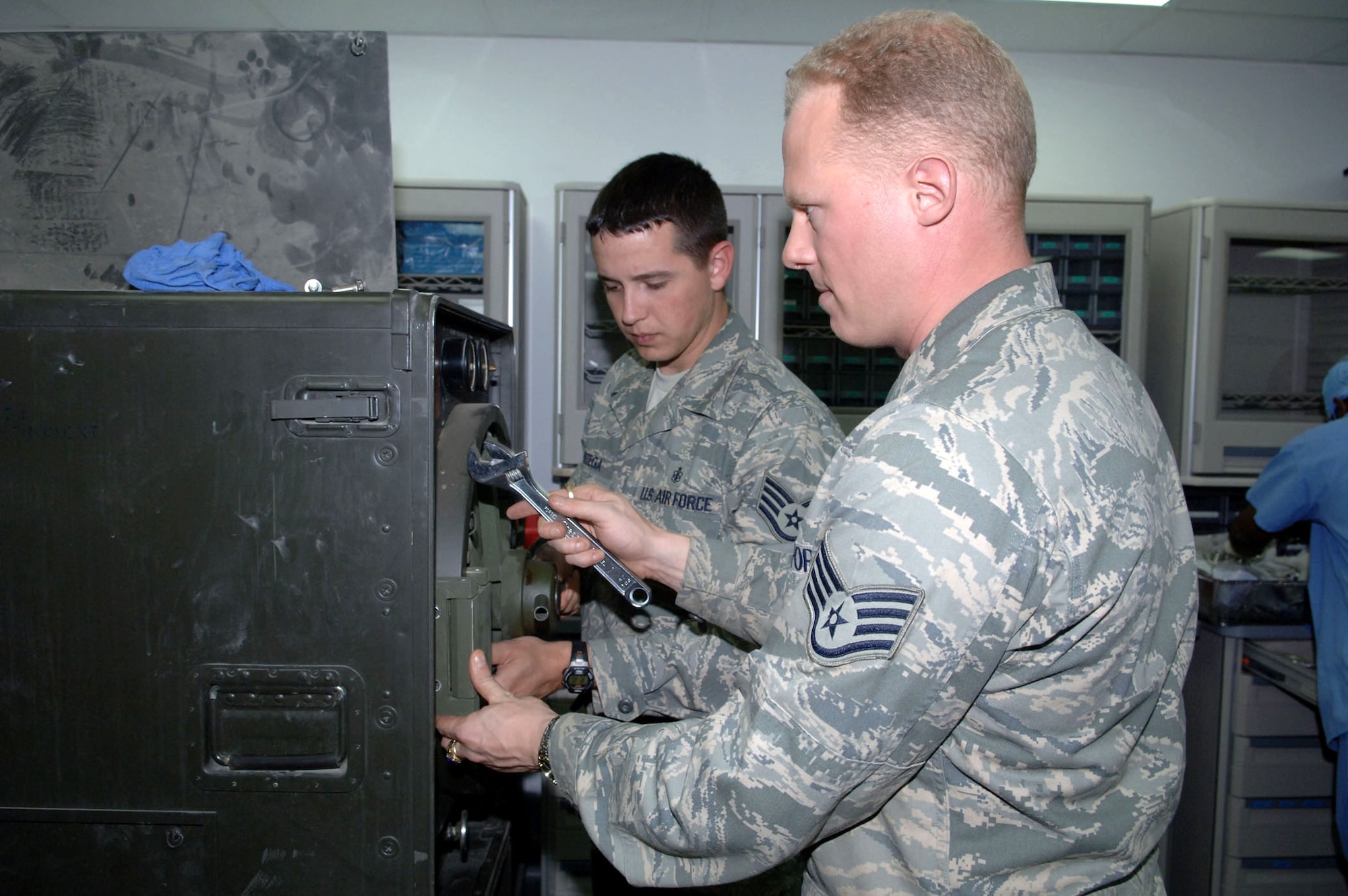 Staff Sgt. Orlando Ortega holds a sterilizer's door in place as Staff Sgt. Brian Cummings uses a wrench to remove a bolt Jan. 12 at Balad Air Base, Iraq. Both are 332nd Expeditionary Medical Support Squadron biomedical equipment technicians. Biomedical equipment repair technicians perform repairs, scheduled maintenance, inspections and calibrations on all biomedical equipment at the Air Force Theater Hospital. Sergeant Ortega is deployed from Barksdale Air Force Base, La. Sergeant Cummings is deployed from Langley Air Force Base, Va. (U.S. Air Force photo/Senior Airman Terri Barriere) 
