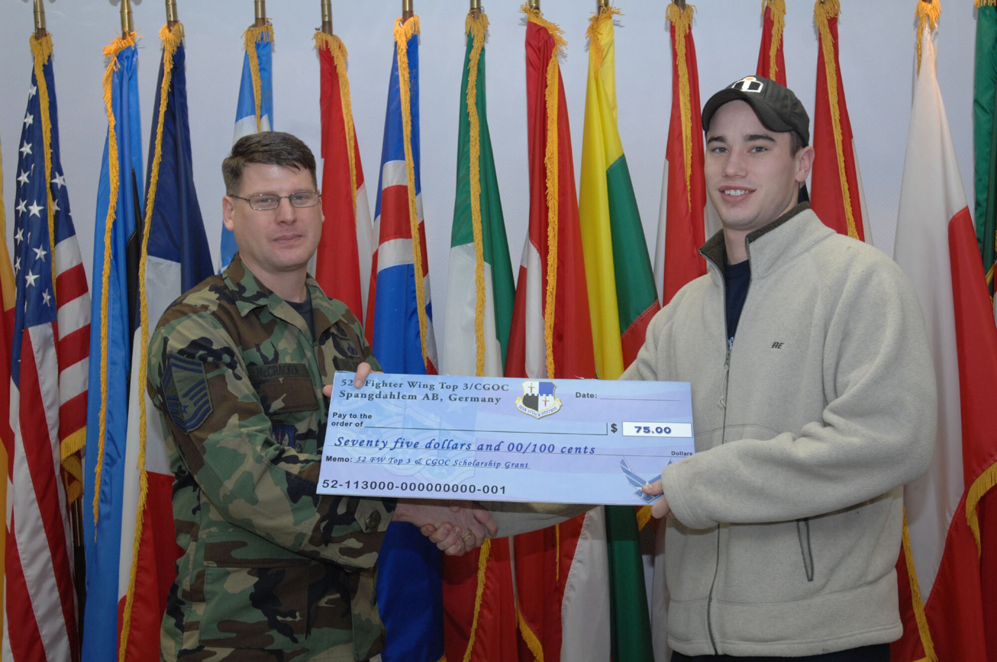 SPANGDAHLEM AIR BASE, Germany – Senior Master Sgt. Patrick McCracken, 52nd Fighter Wing Top 3 Education Committee, presents Senior Airman Joshua Gilbert, 726th Air Mobility Squadron, with a First Book Grant of $75. The First Book program was initiated to encourage Airmen to continue their off-duty education. (U.S. Air Force photo/Airman 1st Class Jenifer Calhoun)