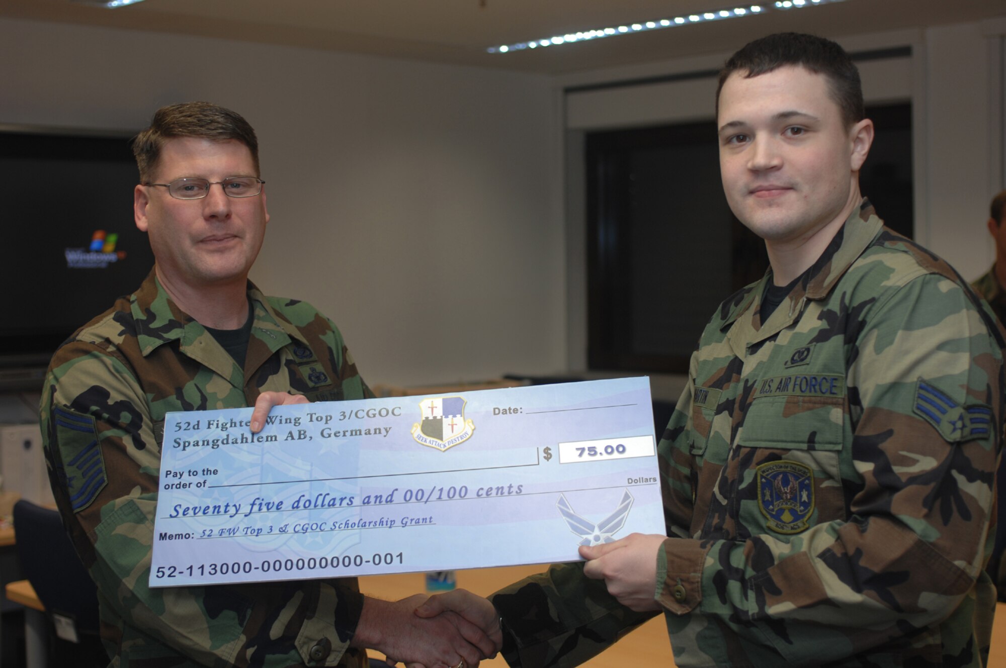 SPANGDAHLEM AIR BASE, Germany – Senior Master Sgt. Patrick McCracken, 52nd Fighter Wing Top 3 Education Committee, presents Senior Airman Casey Martin, 606th Air Control Squadron, with a First Book Grant of $75. The First Book program was initiated to encourage Airmen to continue their off-duty education. (U.S. Air Force photo/Senior Airman Kristin Ruleau)