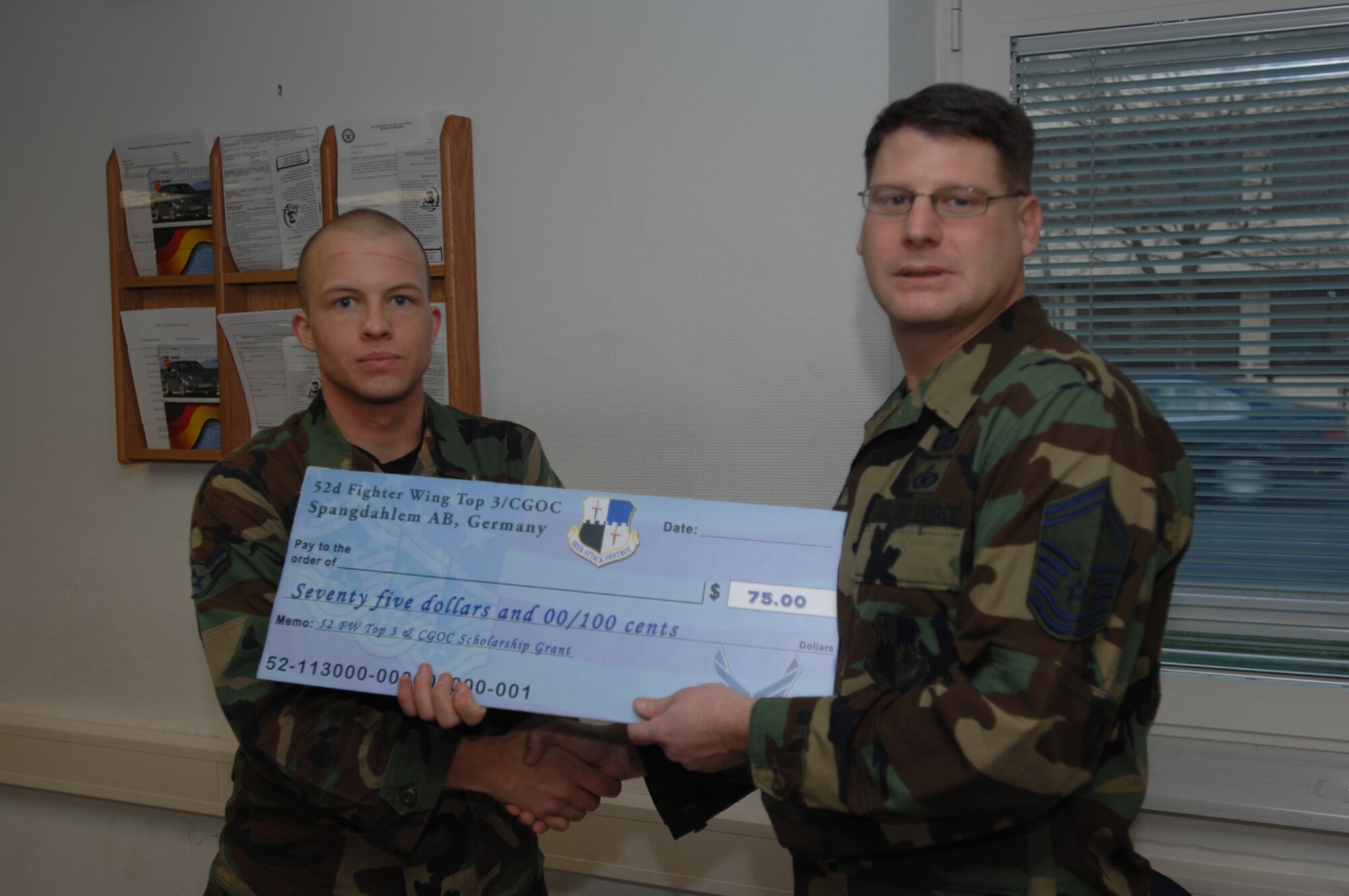 SPANGDAHLEM AIR BASE, Germany – Senior Master Sgt. Patrick McCracken, 52nd Fighter Wing Top 3 Education Committee, presents Airman 1st Class Christopher Sass, 52nd Security Forces Squadron, with a First Book Grant of $75. The First Book program was initiated to encourage Airmen to continue their off-duty education. (U.S. Air Force photo/Senior Airman Kristin Ruleau)