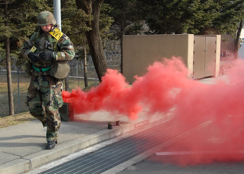 OSAN AIR BASE, Republic of Korea -- Technical Sergeant Walter Swan, a weapons safety manager and exercise evaluation team member, ignites a smoke grenade to indicate a simulated attack during a peninsula-wide exercise at Osan Air Base. The operational readiness exercise tests Team Osan's ability to execute combat operations, receive follow-on forces and defend the base from attack. (U.S. Air Force photo by Senior Master Sergeant Marvin Krause)
