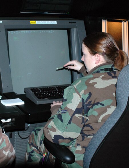 Airman 1st Class Nicole Buck points to a plane on an information panel at the scope control in the 60th Radar Approach Control flight’s operation room. Senior Airman Matthew Barsness was training Airman Buck, one of several new Airmen undergoing training in Travis’ RAPCON flight. (U.S. Air Force photo/Nick DeCicco)