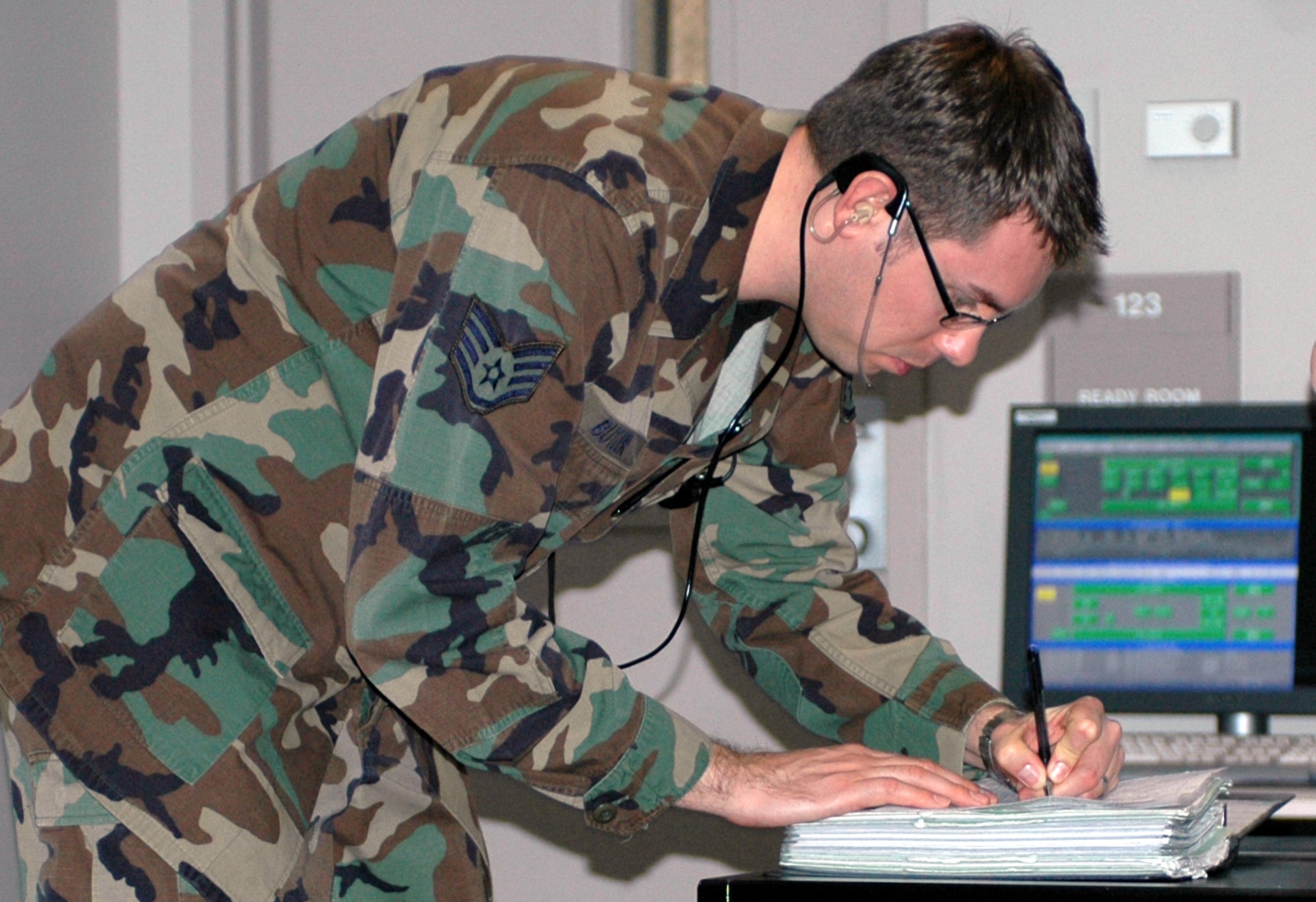 Staff Sgt. Charles Butler writes at the watch commander’s desk in the 60th Radar Approach Control flight’s operation room. Sergeant Butler handles flight data and clearance delivery. (U.S. Air Force photo/Nick DeCicco)