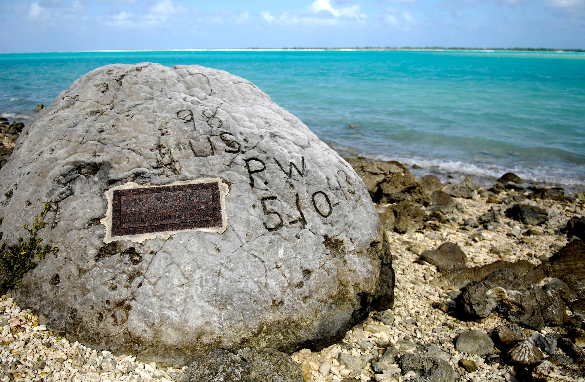 A memorial to prisoners of war is seen Jan. 12 on Wake Island. The "98 Rock" is a memorial for the 98 U.S. civilian contract POWs who were forced by their Japanese captors to rebuild the airstrip as slave labor, then blind-folded and killed by machine gun Oct. 5, 1943. An unidentified prisoner escaped, and chiseled "98 US PW 5-10-43" on a large coral rock near their mass grave, on Wilkes Island at the edge of the lagoon. The prisoner was recaptured and beheaded by the Japanese admiral, who was later convicted and executed for war crimes. (U.S. Air Force photo/Tech. Sgt. Shane A. Cuomo) 
