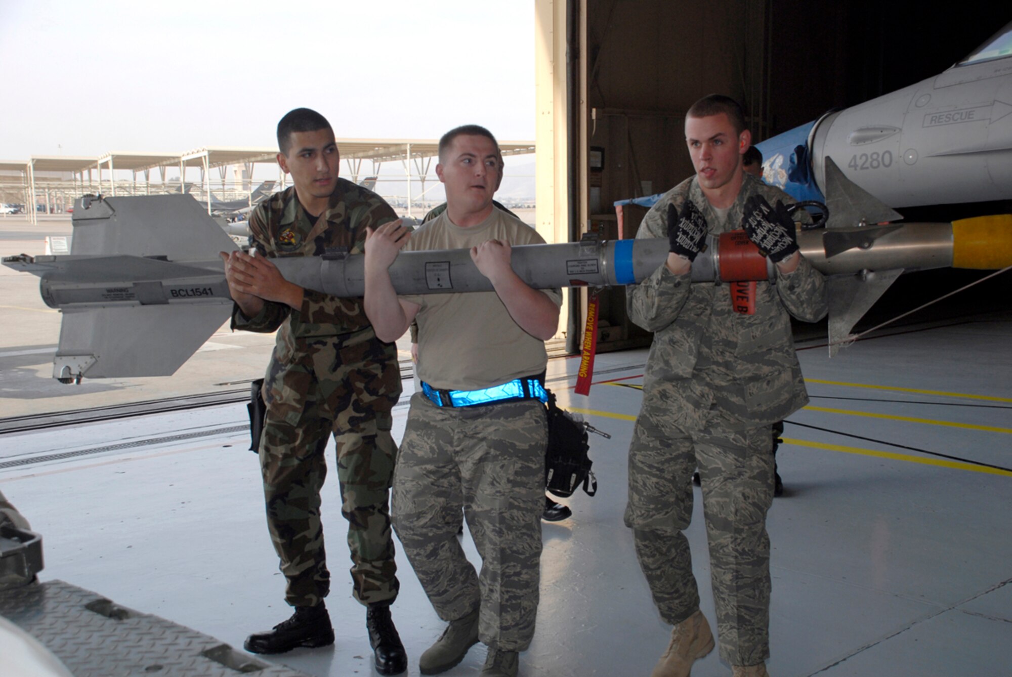 (From left) Airman 1st Class Marcus Irizarry, Staff Sergeant William Massey, and Senior Airman Austin Ward, all members of a weapons load crew from the 62nd Aircraft Maintenance Unit, carry a missile to an F-16 during the Load Crew Competition Jan. 10. In order to win this competition, each crew in the competition must try to assemble weapons on one side of the jet before the other crew finishes. (U.S. Air Force photo by Airman 1st Class Tracie Forte)