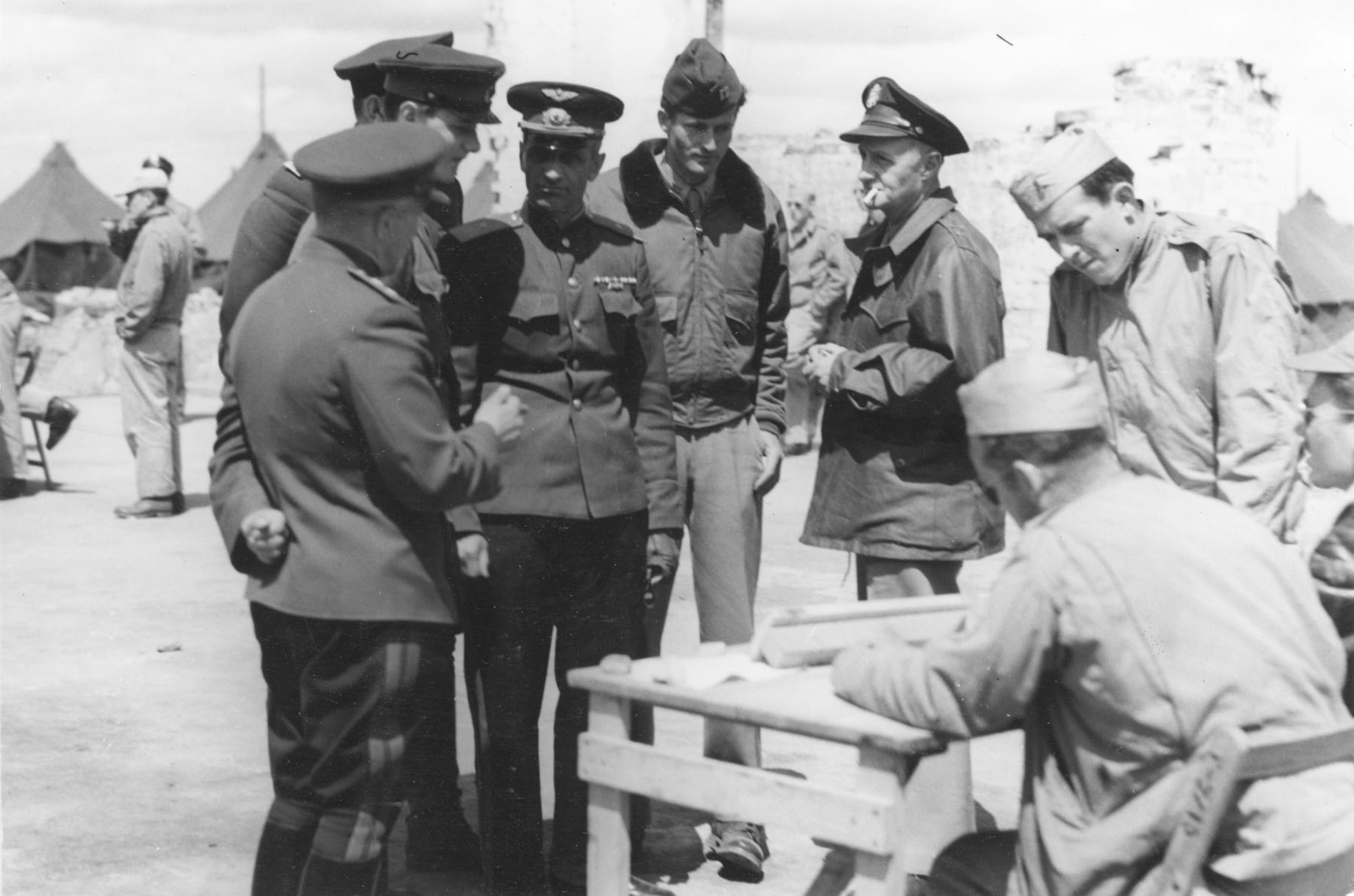 In the ruins of a hangar at Poltava, Gen. Porminov and Gen. Walsh listen to a pilot's report after the mission to Galati. The officer in the center is Capt. Henry Ware, interpreter from Gen. Deane’s staff. (U.S. Air Force photo)