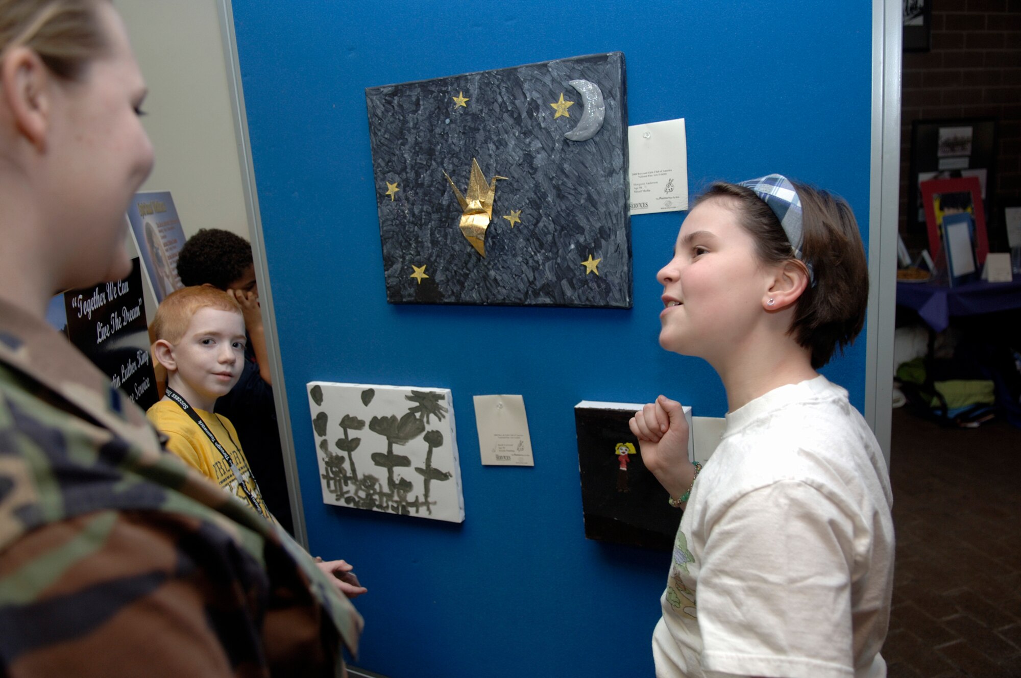 HANSCOM AFB, Mass. – Members of the Hanscom Youth Center recently participated in the Boys & Girls Club National Fine Arts Program. The youth were on hand to talk about their masterpieces on Jan. 11 when the exhibit went on display in the lobby of the Brown Building. Robby Larwood (left) and Margaret Anderson (right) talk about their works of art with 1st Lt. Lisa Spilinek, 66th Air Base Wing Public Affairs Office. The exhibit will be displayed at the Minuteman Club from Jan. 16 to Jan. 23. (U.S. Air Force photo by Jan Abate)