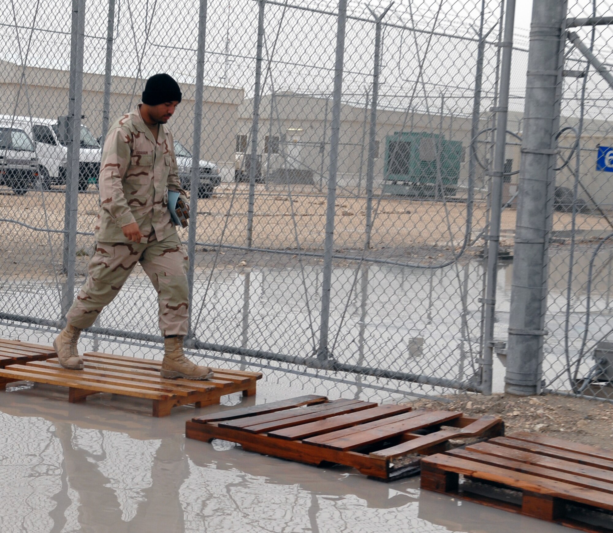 SOUTHWEST ASIA -- Justin Graham, Combined Operations Center contractor, utilizes warehouse pallets Jan.15 to cross a vast puddle of water caused by  recent percipitation at a Southwest Asia air base. The base is entering the rainy season and downpours of rain in the past few days have left some areas of roadway flooded and other areas with pools of standing water.  (U. S. Air Force photo/Senior Airman Domonique Simmons)