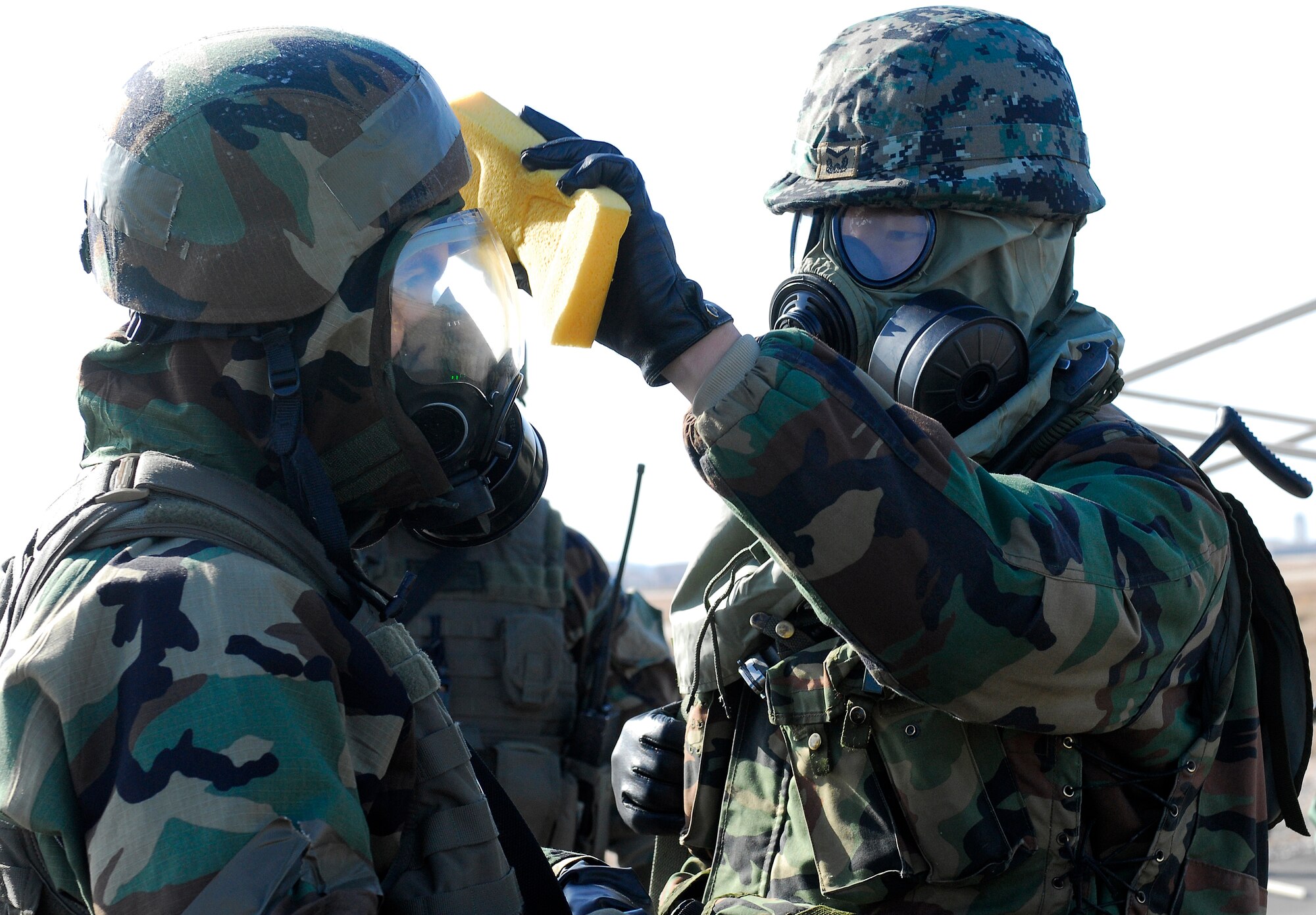KUNSAN AIR BASE, South Korea -- A Republic of Korea Army soldier from 7th Brigade Special Forces helps his American counterpart during a decontamination process here Jan. 16. Republic of Korea Army soldiers and 8th Security Forces Squadron members demonstrate the teamwork necessary to carry out the combined mission of the two allies stationed at Kunsan during a peninsula wide operations readiness exercise. (U.S. Air Force photo/Senior Airman Giang Nguyen)