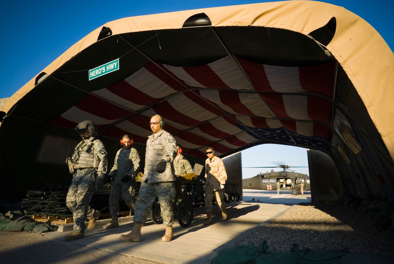 BALAD AIR BASE, Iraq -- Volunteers rush a patient litter through "Hero's Highway" en route to the emergency room at the Air Force Theater Hospital here, Jan. 15. "Hero's Highway" is a canopy that serves as a transition area between the helipad and the AFTH emergency room. The interior roof of the canopy is covered by a huge American flag that signals to wounded troops that they are safe. The flag was donated by the cadets of the Marion Military Institute. (U.S. Air Force Photo/Master Sgt. John R. Nimmo, Sr.)