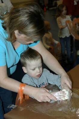 MINOT AIR FORCE BASE, N.D.-- Jennifer Wells, wife of Capt. Jeremy Wells of the 91st Missile Maintenance Squadron, helps her son Josiah make a "snowball" out of popcorn and marshmallows during the winter carnival at the David C. Jones Youth Center Jan. 16. The winter carnival is an annual event  the youth center puts on for  parents and their children  to participate in games and activities outside of their homes. (U. S. Air Force photo by Airman 1st Class Cassandra Jones)