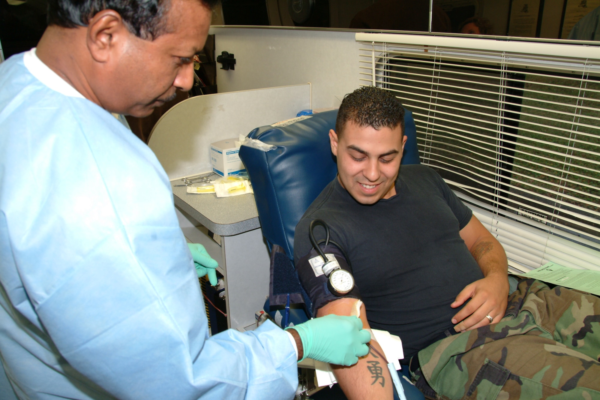 Shane Sooknanan, Northwest Florida Blood Center mobile supervisor and phlebotomist, checks the needle site on blood donor Senior Airman Alberto Miranda, 16th Electronic Warfare Squadron advanced program team member, Wednesday during the 53d Wing blood drive at Eglin Air Force Base.  Air Force photo by Capt. Carrie Kessler.