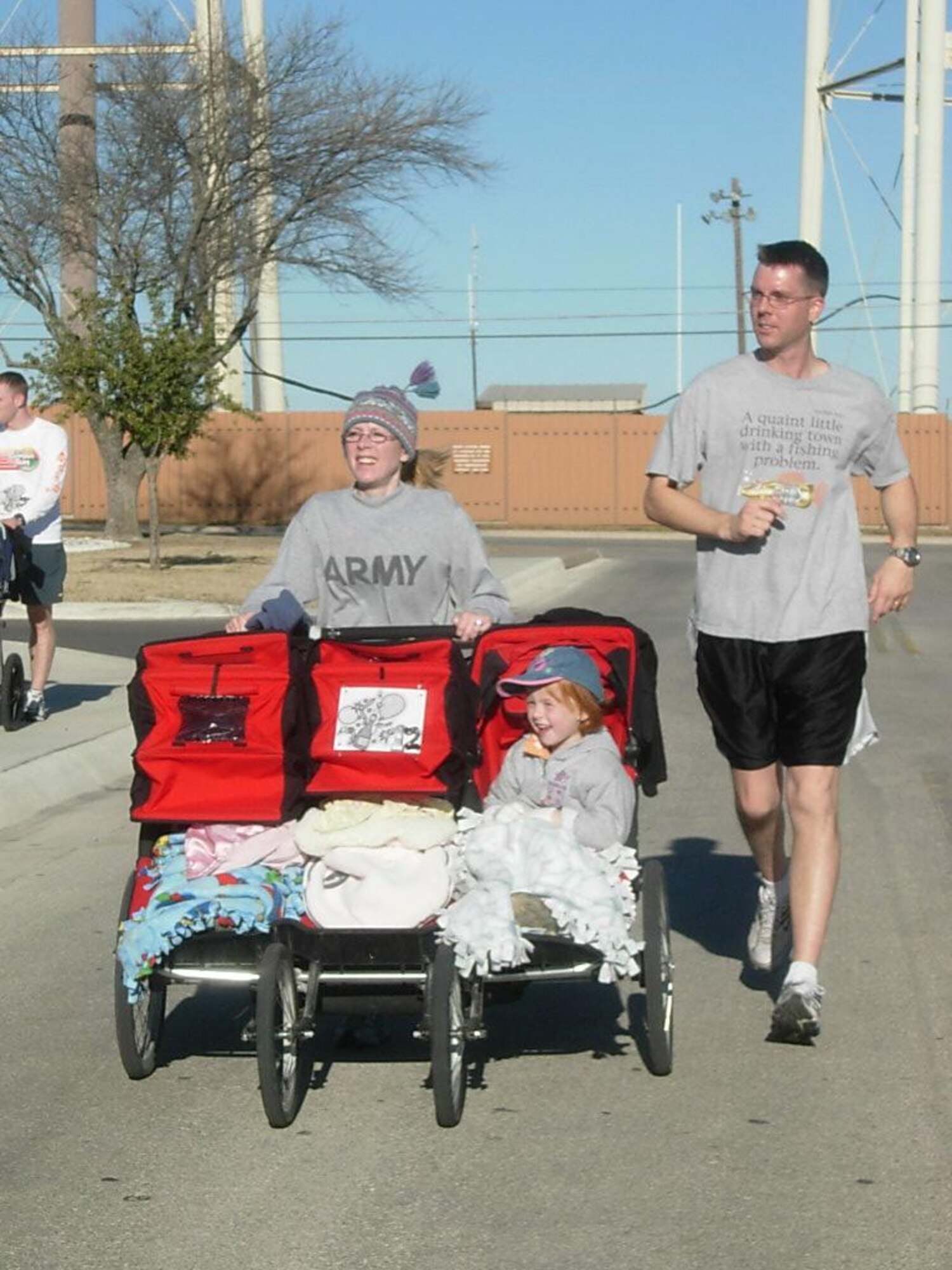 LAUGHLIN AIR FORCE BASE, Texas- Second Lieutenant David Johnson, 85th Flying Training Squadron, runs alongside his wife, Jennifer Johnson as she pushes their three children during Laughlin's annual 5K fun run/race.  Lieutenant Johnson and his wife are regular participants in local and state marathons said Lauren Koether, Programs Director for the 47th Force Support Squadron.  (U.S. Air Force photo by Lauren Koether)   