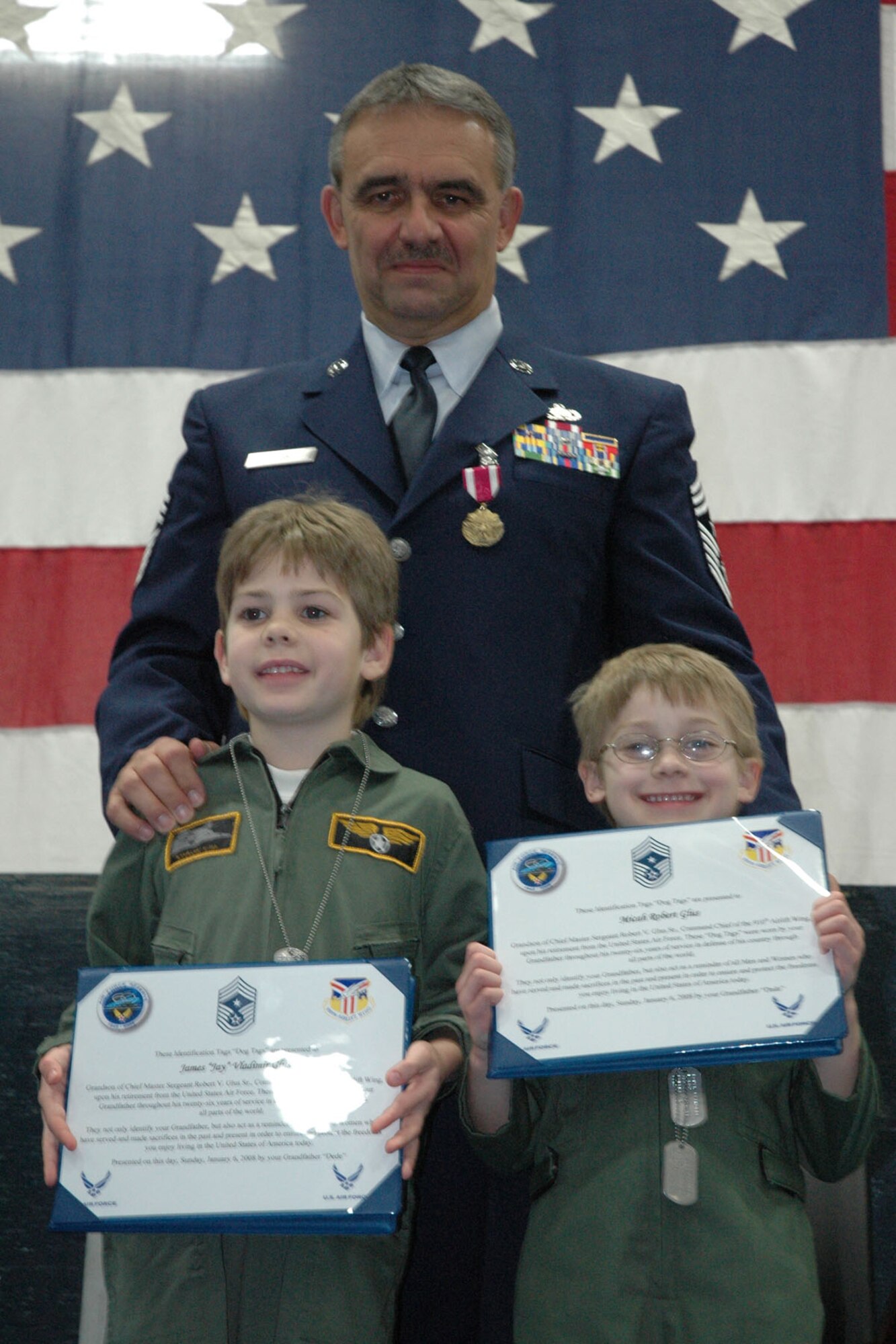 YOUNGSTOWN AIR RESERVE STATION, Ohio — Air Force Reserve Chief Master Sgt. Robert V. Glus Sr., command chief master sergeant of the 910th Airlift Wing, presents his identification dog tags to his grandsons, James "Jay" Vladimir Glus,left, and Micah Robert Glus, during the chief's retirement ceremony Jan. 6, 2008. U.S. Air Force photo/Tech. Sgt. Bob Barko Jr.