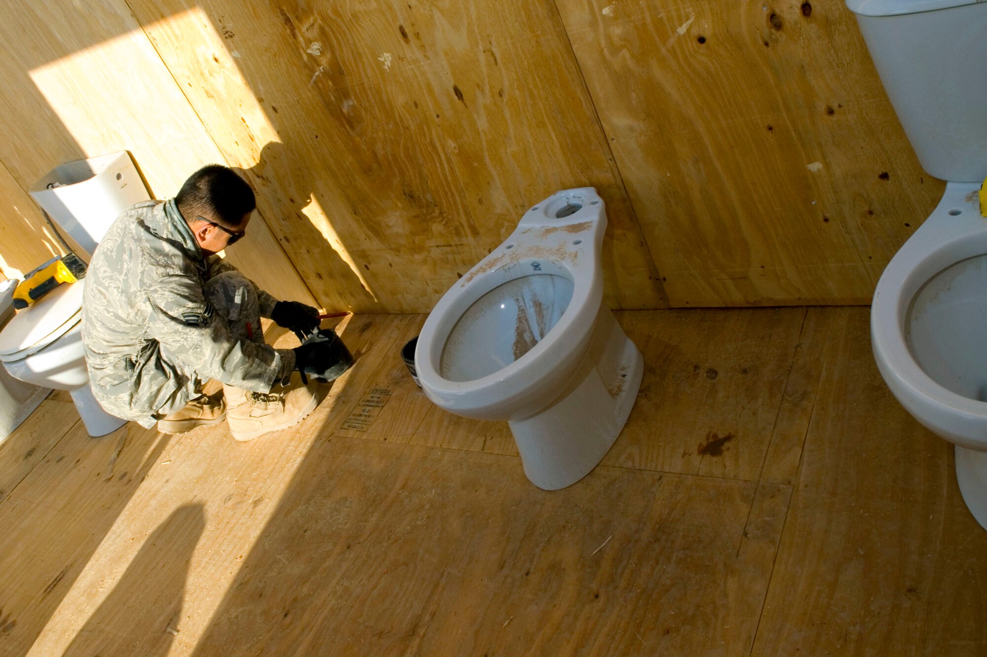Senior Airman Ernesto Racoma measures the distance between toilets on a shower latrine unit Jan. 15 at Balad Air Base, Iraq. The placement measurements allow the Airman to ensure a proper fit when installing the toilets. Airman Racoma, a 732nd Expeditionary Civil Engineer Squadron utility technician, is deployed from Beale Air Force Base, Calif. (U.S. Air Force photo/Staff Sgt. Joshua Garcia) 
