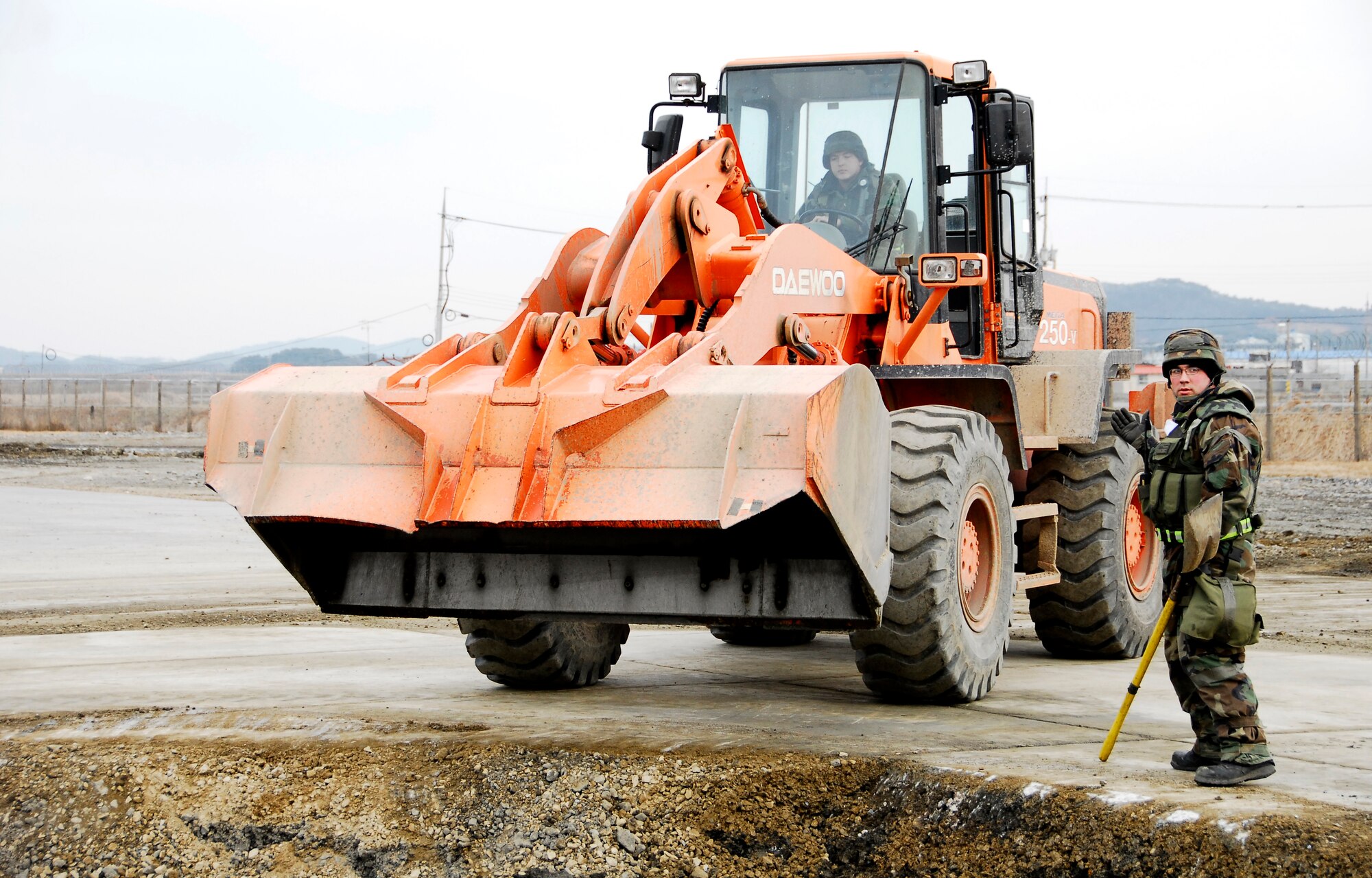 KUNSAN AIR BASE, South Korea -- Senior Airman Sean Bilodeau guides Senior Airman Kyle McKay, both from the 8th Civil Engineer Squadron, in as they perform airfield damage repair during a peninsula wide operations readiness exercise (PENORE) here Jan 17.  The PENORE is conducted to ensure members of the Wolf Pack remain ready to execute the mission of maintaining peace and stability in the region.  (U.S. Air Force photo/Tech Sgt. Quinton T. Burris) 