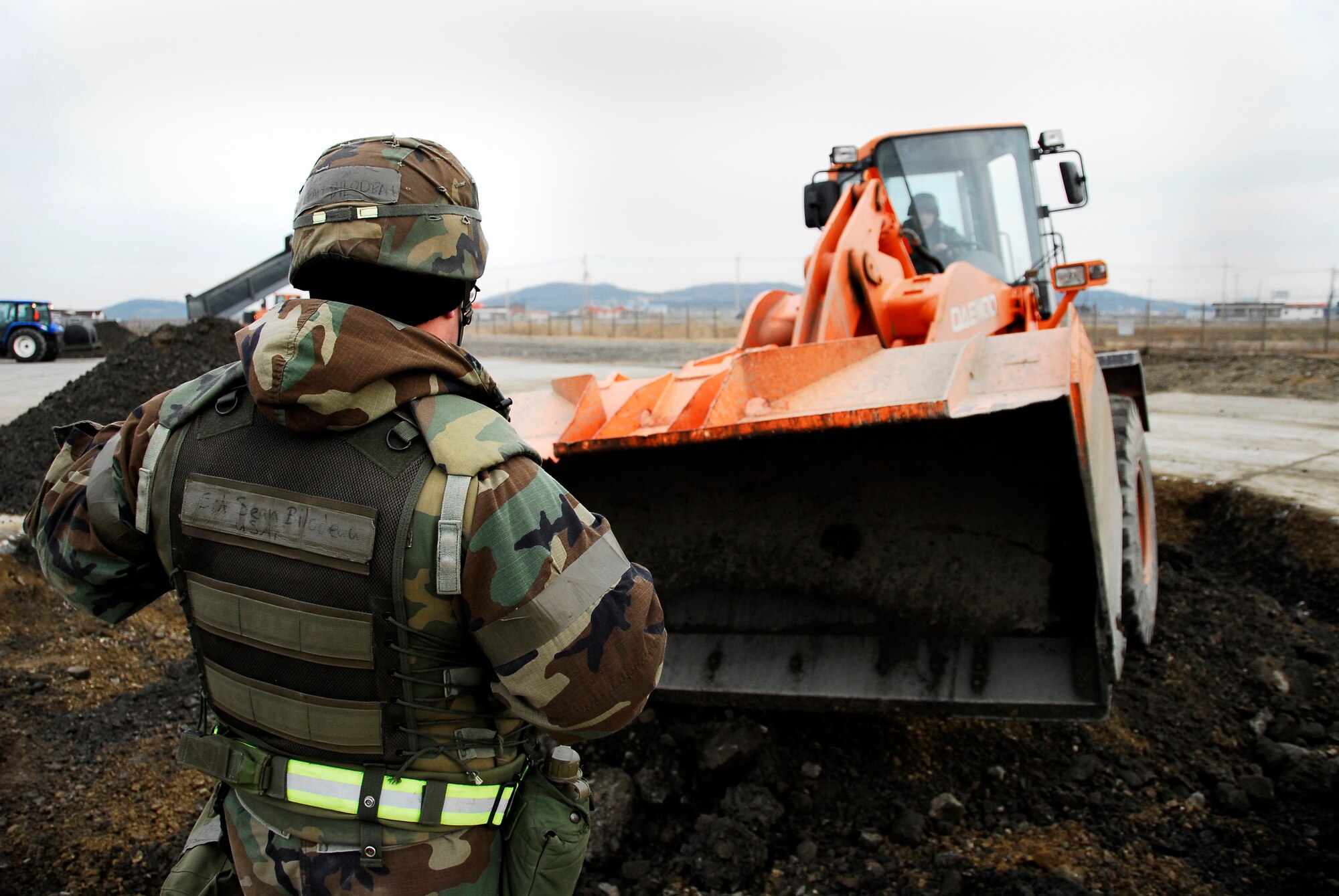 KUNSAN AIR BASE, South Korea -- Senior Airman Sean Bilodeau guides Senior Airman Kyle McKay, both from the 8th Civil Engineer Squadron, in as they perform airfield damage repair during a peninsula wide operations readiness exercise (PENORE) here Jan 17.  The PENORE is conducted to ensure members of the Wolf Pack remain ready to execute the mission of maintaining peace and stability in the region.  (U.S. Air Force photo/Tech Sgt. Quinton T. Burris) 