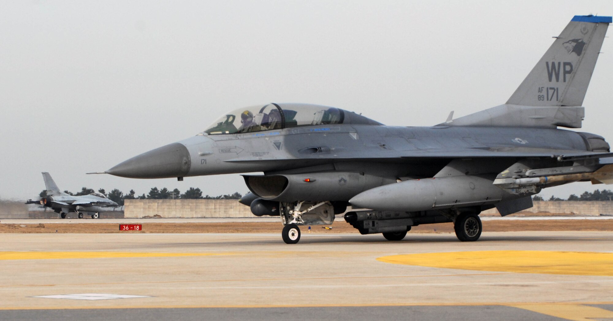 KUNSAN AIR BASE, South Korea -- An F-16 Fighting Falcon from the 35th Fighter Squadron (front) stands by as an F-16 from the 111th FS, Republic of Korea Air Force, (back) takes off for joint flying operations during the peninsula wide operations readiness exercise here Jan. 17. The exercise is conducted to ensure members of the Wolf Pack remain ready to execute its mission of "Defending the Base, Accepting Follow on Forces and Taking the Fight North." (U.S. Air Force photo/Senior Airman Steven R. Doty)