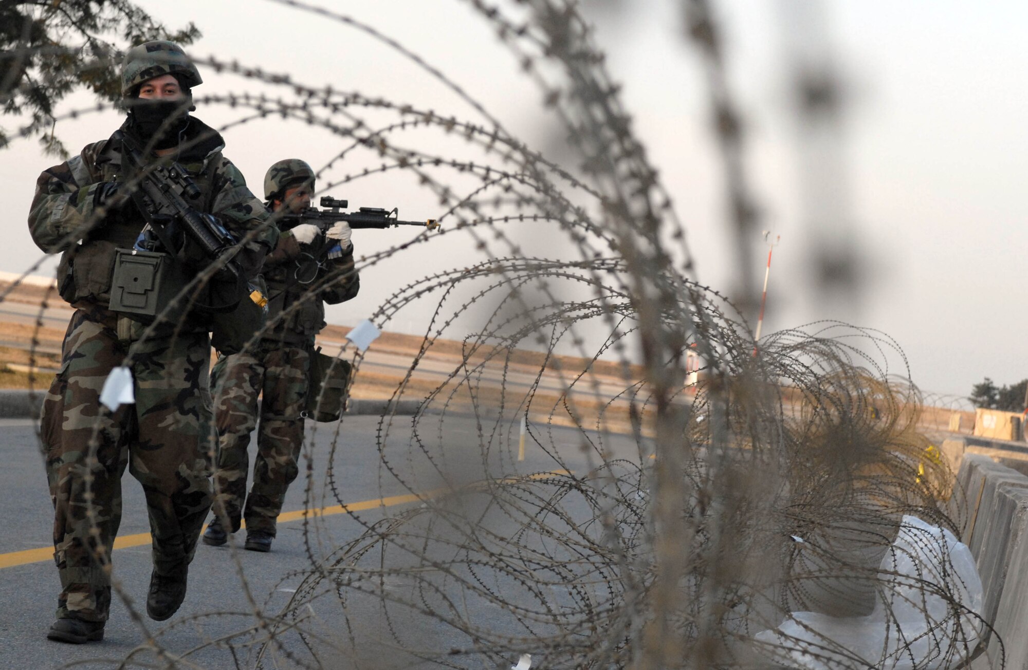 KUNSAN AIR BASE, South Korea -- Senior Airmen Alejandro DeLaFuente (front) and Anthony Leonard (back), 8th Security Forces Squadron, inspect the perimeter for enemy forces after a simulated attack on the Wing Operations Center during the peninsula wide operations readiness exercise here Jan. 17. The exercise is conducted to ensure members of the Wolf Pack remain ready to execute its mission of "Defending the Base, Accepting Follow on Forces and Taking the Fight North." (U.S. Air Force photo/Senior Airman Steven R. Doty)