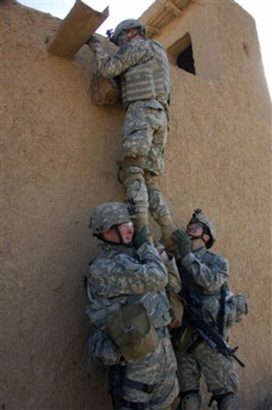U.S. Army Pfc. Ryan Mahan and Spc. Stephen McLain hoist Pfc. Ryan Springstead as he looks over a wall to see if they can enter a house through the roof of a building in Chinchal, Iraq, on Jan. 8, 2008.  The soldiers are assigned to 3rd Platoon, Alpha Troop, 1st Squadron, 71st Cavalry Regiment, 1st Brigade Combat Team, 10th Mountain Division.  