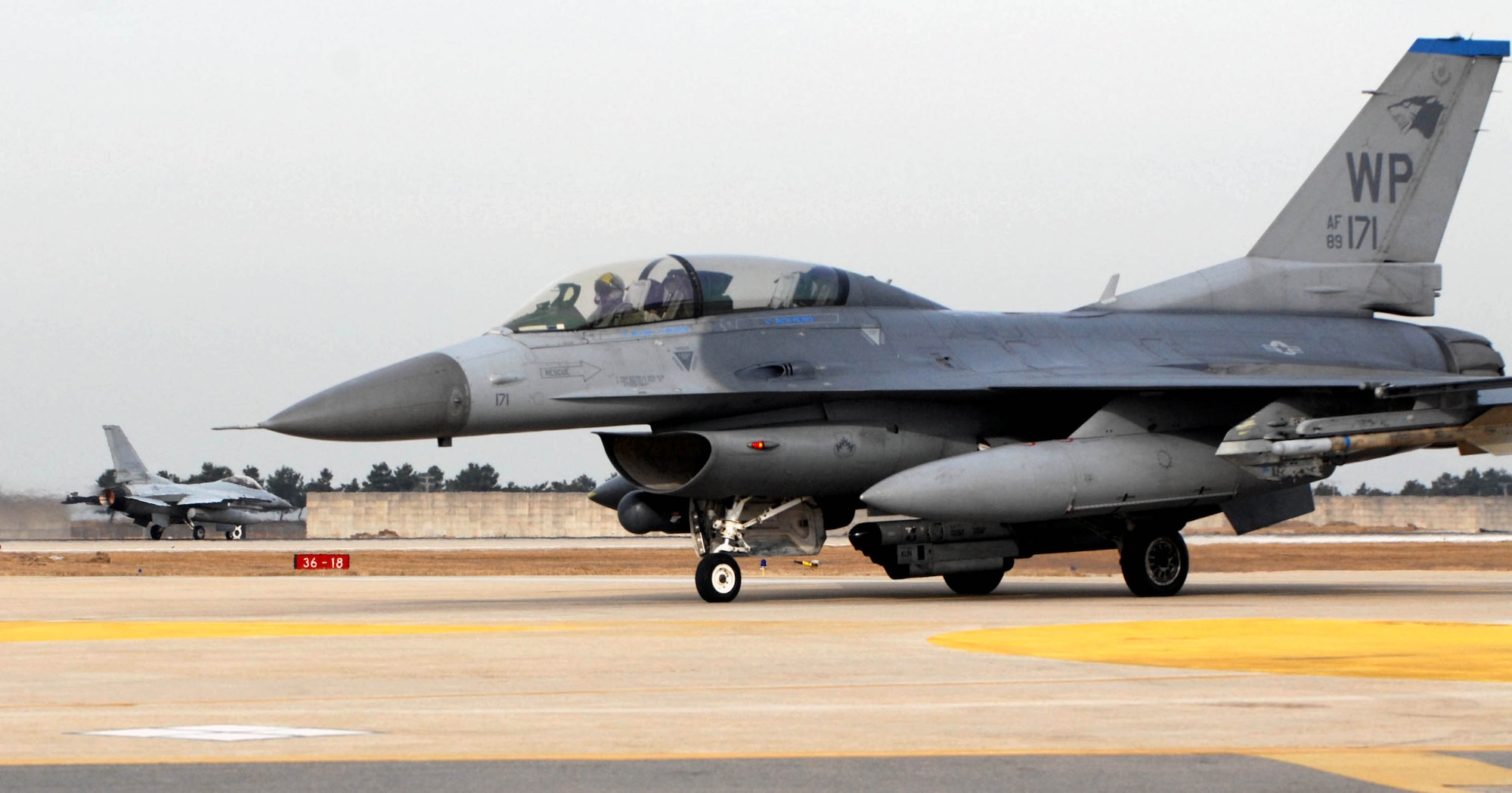 An F-16 Fighting Falcon from the 35th Fighter Squadron (front) stands by as an F-16 from the 111th FS, South Korea air force, (back) takes off for joint flying operations during the peninsula wide operational readiness exercise Jan. 17 at Kunsan Air Base, South Korea. (U.S. Air Force photo/Senior Airman Steven R. Doty)
