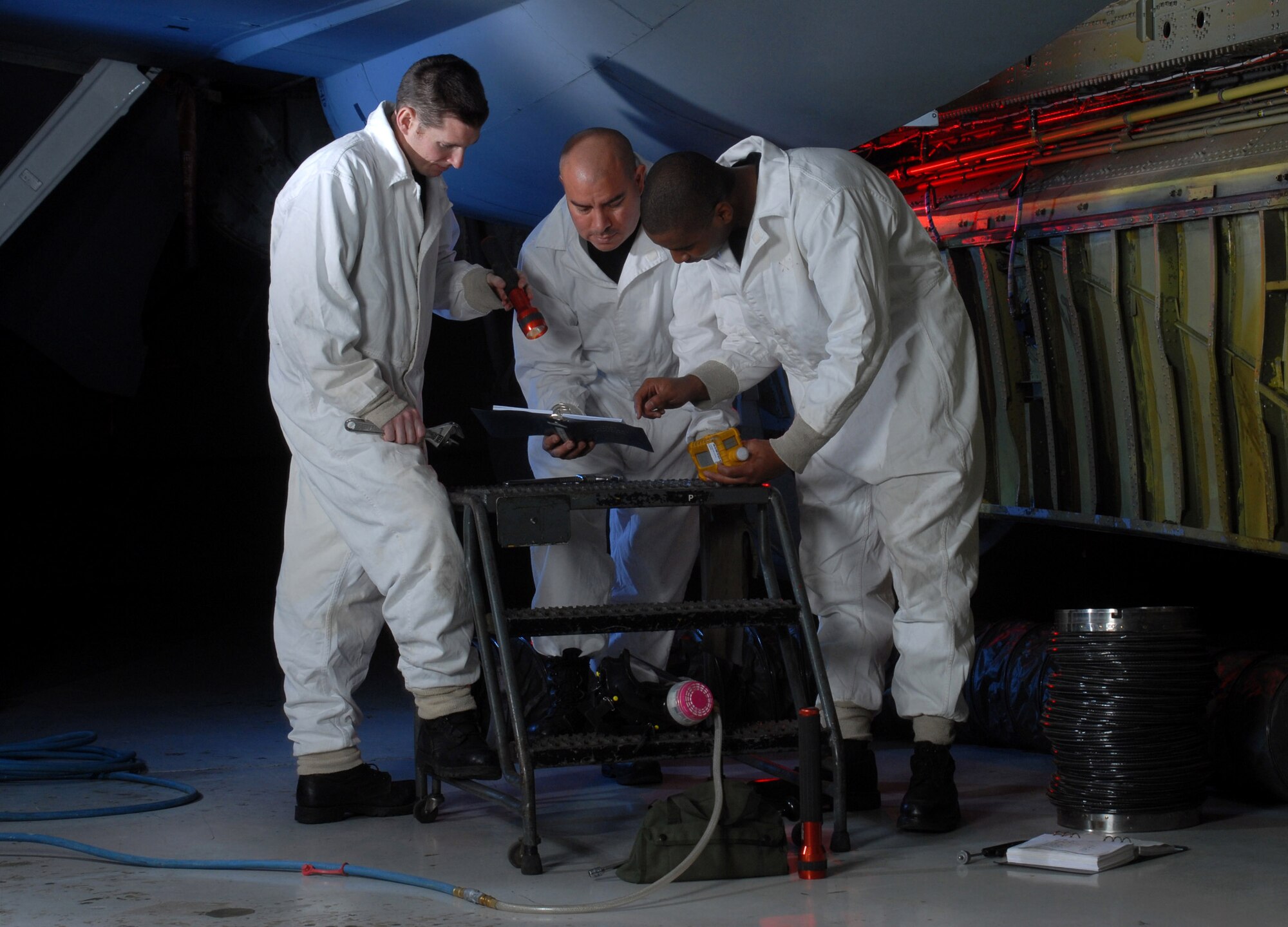 Staff Sgt. Ryan Slanina (from left), Tech. Sgt. Tim Burrola and Senior Airman David Skannal reference their technical order before inspecting a fuel tank of a KC-135 Stratotanker Jan. 9 at March Air Reserve Base, Calif. The three are all fuel cell technicians from the 452nd Maintenance Squadron. (U.S. Air Force photo/Val Gempis)