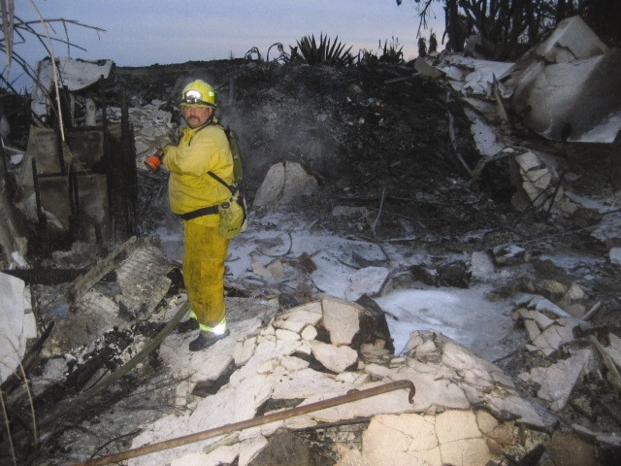 Fire fighter Gary Richards does salvage and overhaul at a house that was lost in the Malibu Corral Canyon Fire. Four personnel from the March ARB Fire Department along with Engine-8 were sent to Malibu Nov. 8 - 10 to assist with the fires. The department, which falls under the 452nd Civil Engineering Squadron, has a dual mission supporting both the base as well as assisting the local community.  (U.S. Air Force photo)