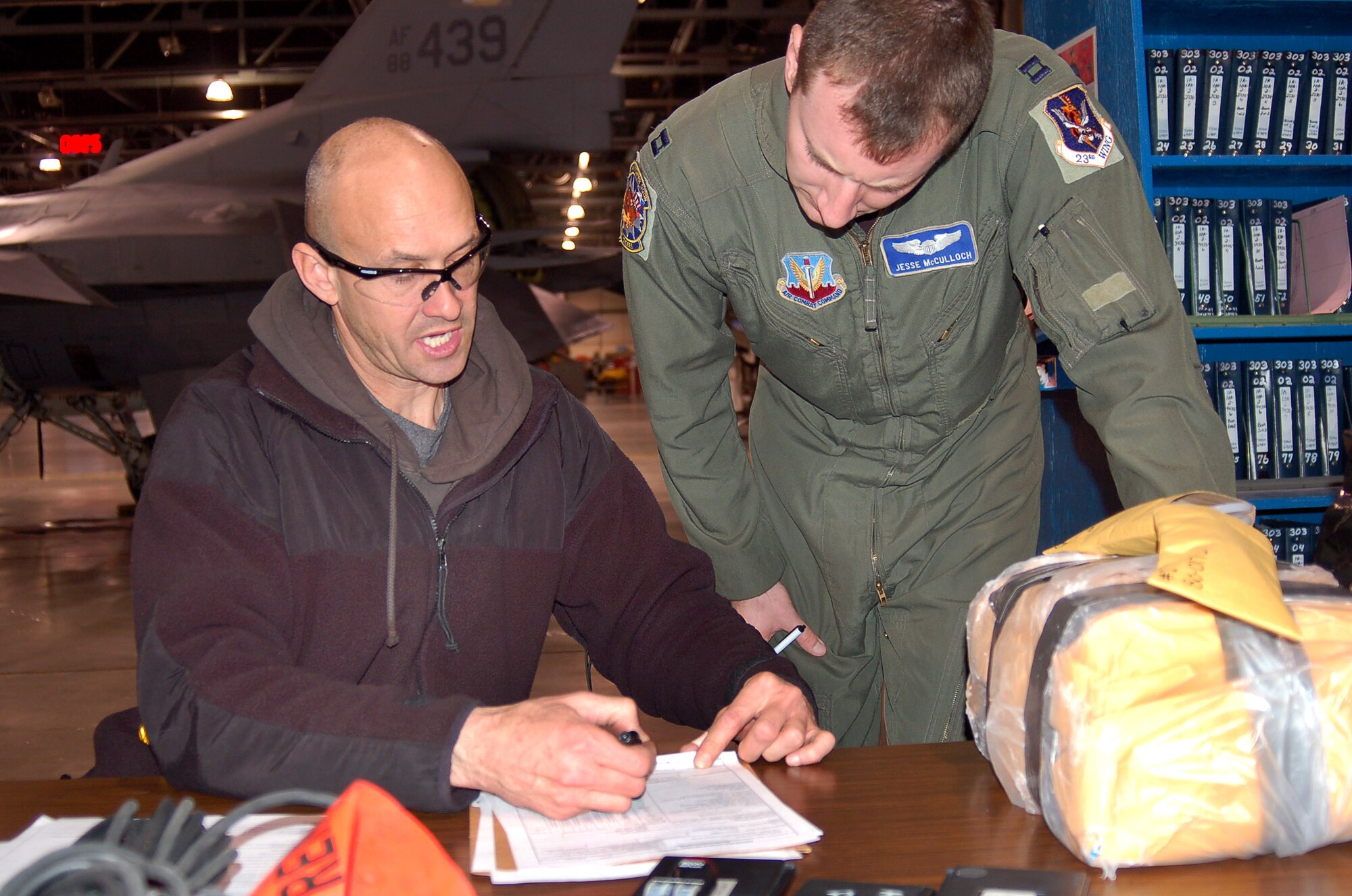 Andrew Selph and Capt. Jesse McCulloch discuss paperwork details that will send A-10 Thunderbolt II aircraft 80-0172 to Moody Air Force Base, Ga. The aircraft is the 100th A-10 to receive the Precision Engagement modification installed by the 571st Aircraft Maintenance Squadron at Hill Air Force Base, Utah, which will extend the its service life until 2028. (U.S. Air Force photo/Bill Orndorff) 