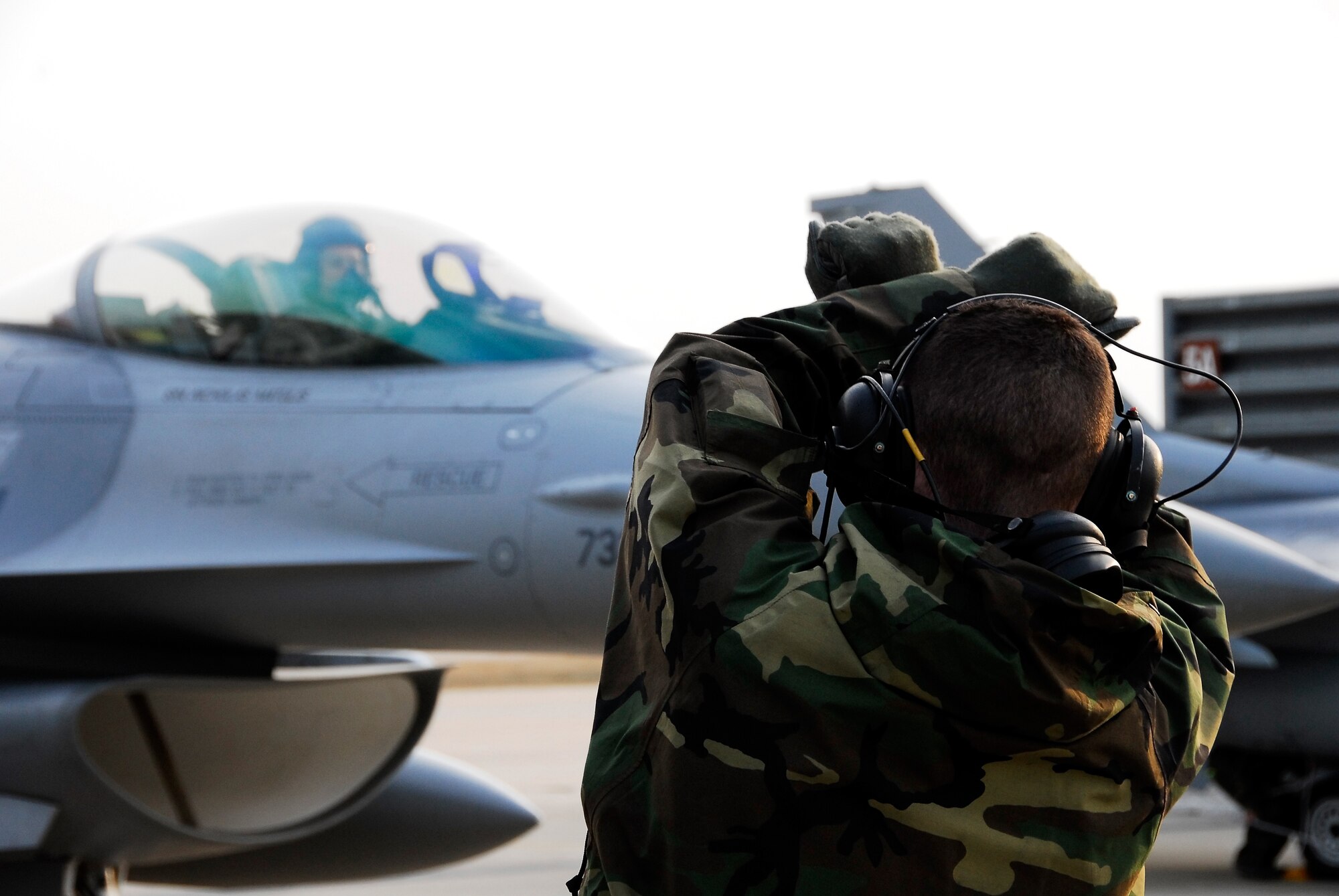 KUNSAN AIR BASE, South Korea -- A member of the 8th Aircraft Maintenance Squadron marshals in an F-16 that is part of the Common Configuration Implementation Program after a flight from Eielson Air Base, Alaska here Jan 18. The 80th Fighter Squadron will be receiving 18 CCIP Block 40 jets from the Alaskan based unit and Eielson will in-turn receive the 80th FS Block 30 jets for an aggressor squadron.  (U.S. Air Force photo/Tech Sgt. Quinton T. Burris)