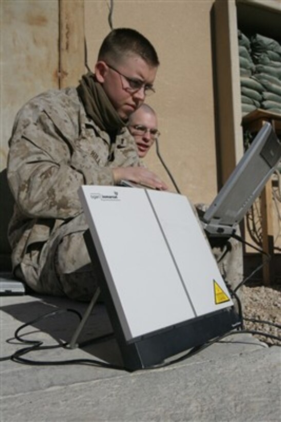 U.S. Marine Corps Cpl. Tyler Hill (left) works on a laptop computer as he learns how to set up a broadband global area network system from Sgt. Jacob Brewer at Camp Ripper, Iraq, on Jan. 16, 2008.  Hill, and other photographers from Combat Camera, Regimental Combat Team 5, uses the system to transmit digital photography to higher headquarters.  