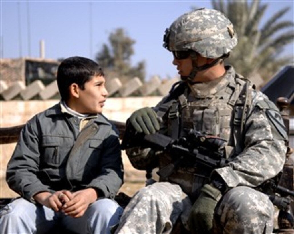 A U.S. Army soldier from 1st Brigade Combat Team, 1st Cavalry Division talks with a young Iraqi boy in Hor al Bosh, Iraq, Jan. 12, 2008.