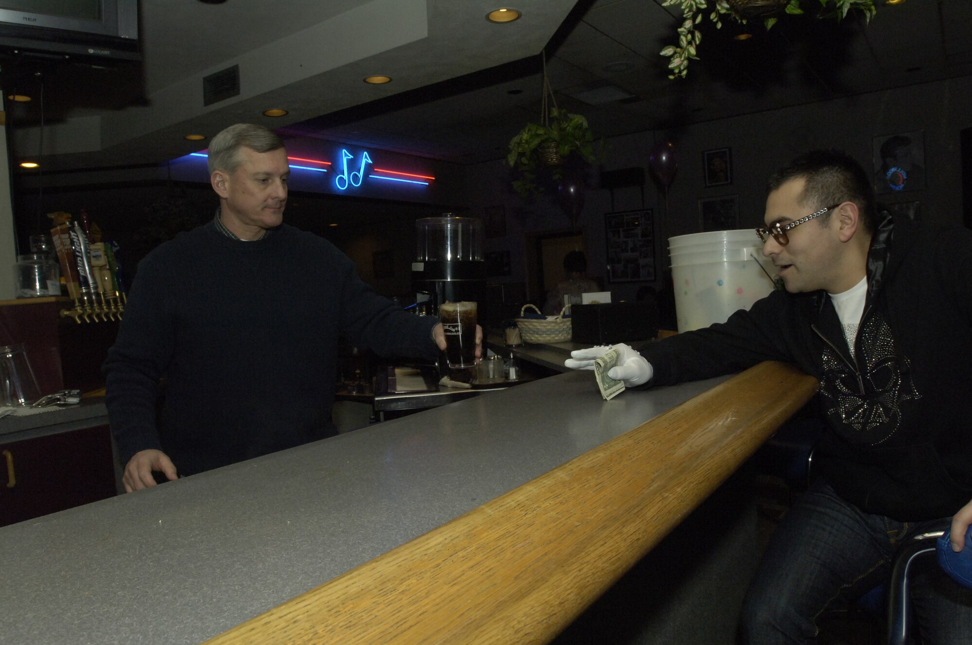 FAIRCHILD AIR FORCE BASE, Wash. – Chief Master Sgt. John Elder, 92nd Medical Group superintendent, serves a soda to Senior Airman Nemesio Perez during the Totally Awesome 80’s celebration at Club Fairchild Jan. 18. (U.S. Air Force Photo/Senior Airman Eunique Stevens)