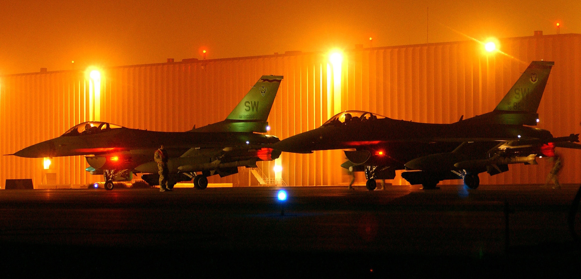 F-16 Fighting Falcons wait on the "hot ramp" at a forward-deployed location while maintenance crews ready the weapons for a night mission. The F-16s are from the 20th Fighter Wing at Shaw Air Force Base, S.C., and they are flying Operation Iraqi Freedom missions for the 363rd Expeditionary Fighter Squadron. (U.S. Air Force photo/Staff Sgt. Matthew Hannen)  
