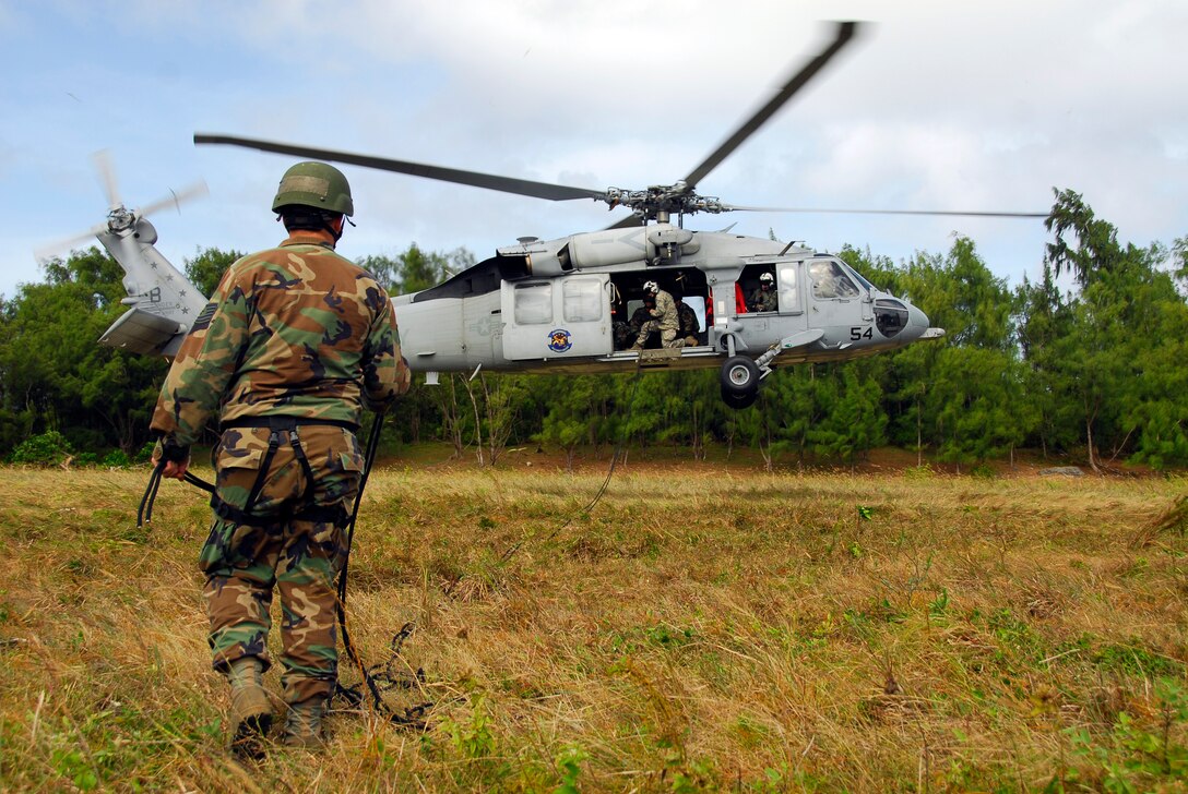 A member of the 554th RED HORSE Squadron assists Tech. Sgt. Todd Reeve, the NCOIC of the 554th RED HORSE Squadron's Air Assault team, in extending a repelling rope from an HH60 helicopter in preparation for helicopter insertion training. (U.S. Air Force photo/Airman 1st Class Daniel Owen)