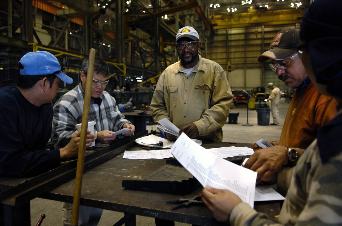 Workers at Force Protection Industries Inc. look over paperwork to make
