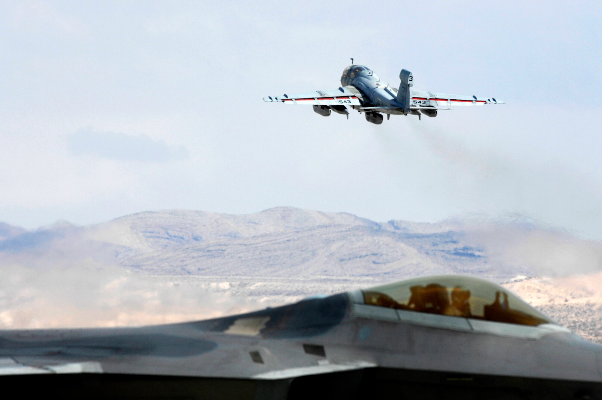 NELLIS AIR FORCE BASE, Nev.—An EA-6 Prowler from the 134th Electronic Attack Squadron, Naval Air Station Whidbey Island, Wash., takes off while an F-22 Raptor taxies out for its mission here Jan. 22. Both aircraft are at Nellis participating in Red Flag 8-2.1, which is a multi-national exercise providing pilots with a realistic environment to practice combat scenarios. The experience gained during the exercise is vital to the survival of pilots in combat. (U.S. Air Force photo by Master Sgt. Robert W. Valenca)
