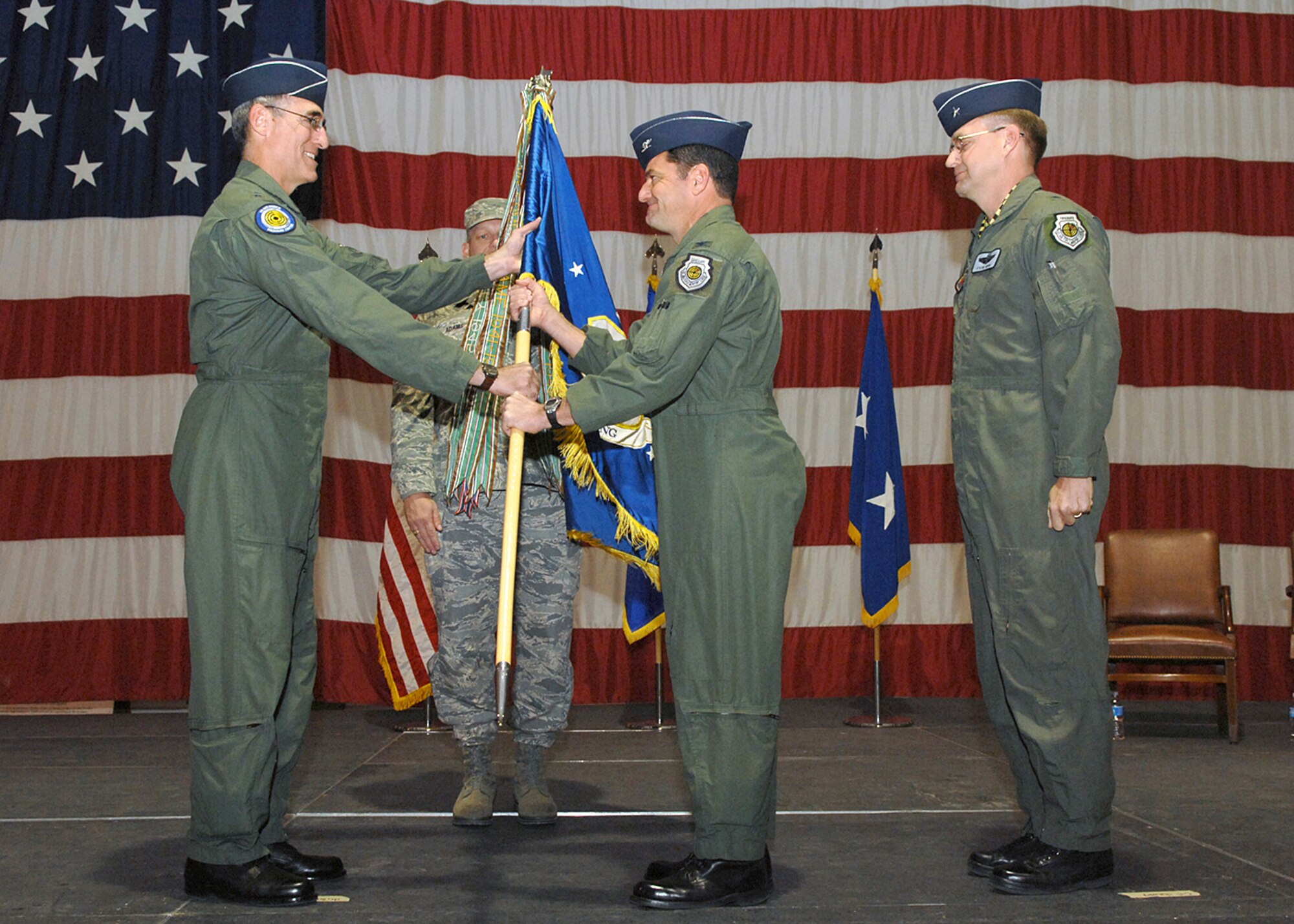 Maj. Gen. R. Mike Worden (left), U.S. Air Force Warfare Center commander, passes the 57th Wing guidon to Col. Russell Handy as outgoing 57th Wing commander Brig. Gen. Stephen Hoog (right) looks on during a change of command ceremony at the Thunderbird hangar here Jan. 18.  General Hoog relinquished command of the 57th Wing to Colonel Handy to take command of the U.S. Air Force Warfare Center. (U.S. Air Force photo by Senior Airman Kasabyan D. McGarvey) 