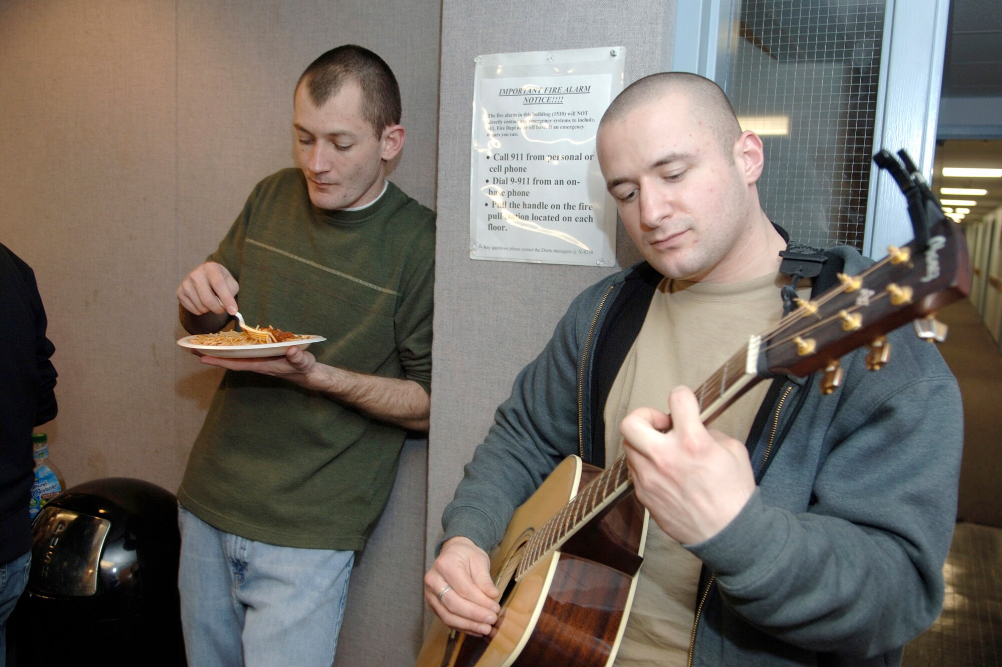 HANSCOM AFB, Mass. -- Airman 1st Class Jonathan Blanck, Air Force Research Laboratory, strums his guitar while Senior Airman Christopher Colgan, 66th Mission Support Group, samples some of the food provided at a Dorm Dinner Jan. 22. The Dorm Dinner was hosted by the Base Chapel. (U.S. Air Force photo by Jan Abate.)