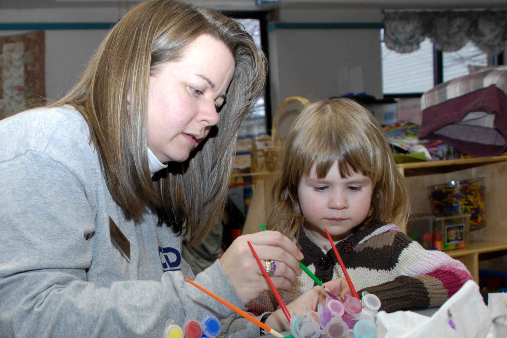 HANSCOM AFB, Mass. – Pre-school children from Room 9 at the Child Development Center had some face painting fun on Jan. 22. The children painted their faces and paraded around the center with musical instruments to serenade other classrooms. Pictured here Tracey Clancy (left), Room 9 care-giver prepares to paint the face of Isabelle Fisher. (U.S. Air Force photo by Linda LaBonte Britt)