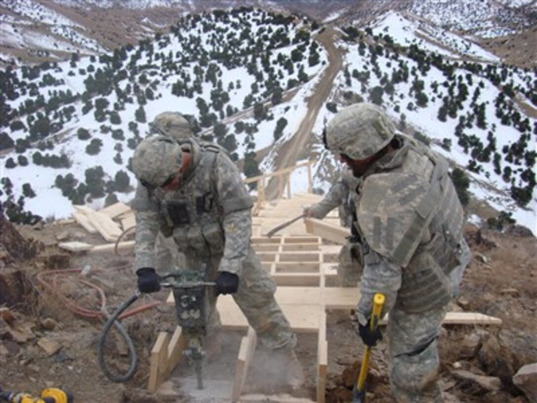 U.S. Army Spcs. Nathan Waddell and Kristopher Hammond use a jackhammer and hand tools as they work on anchoring a stairwell leading to an outpost on a mountain in Afghanistan on Jan. 15, 2008.  Waddell and Hammond are attached to Bravo Company, 864th Engineer Battalion, out of Fort Lewis, Wash.  