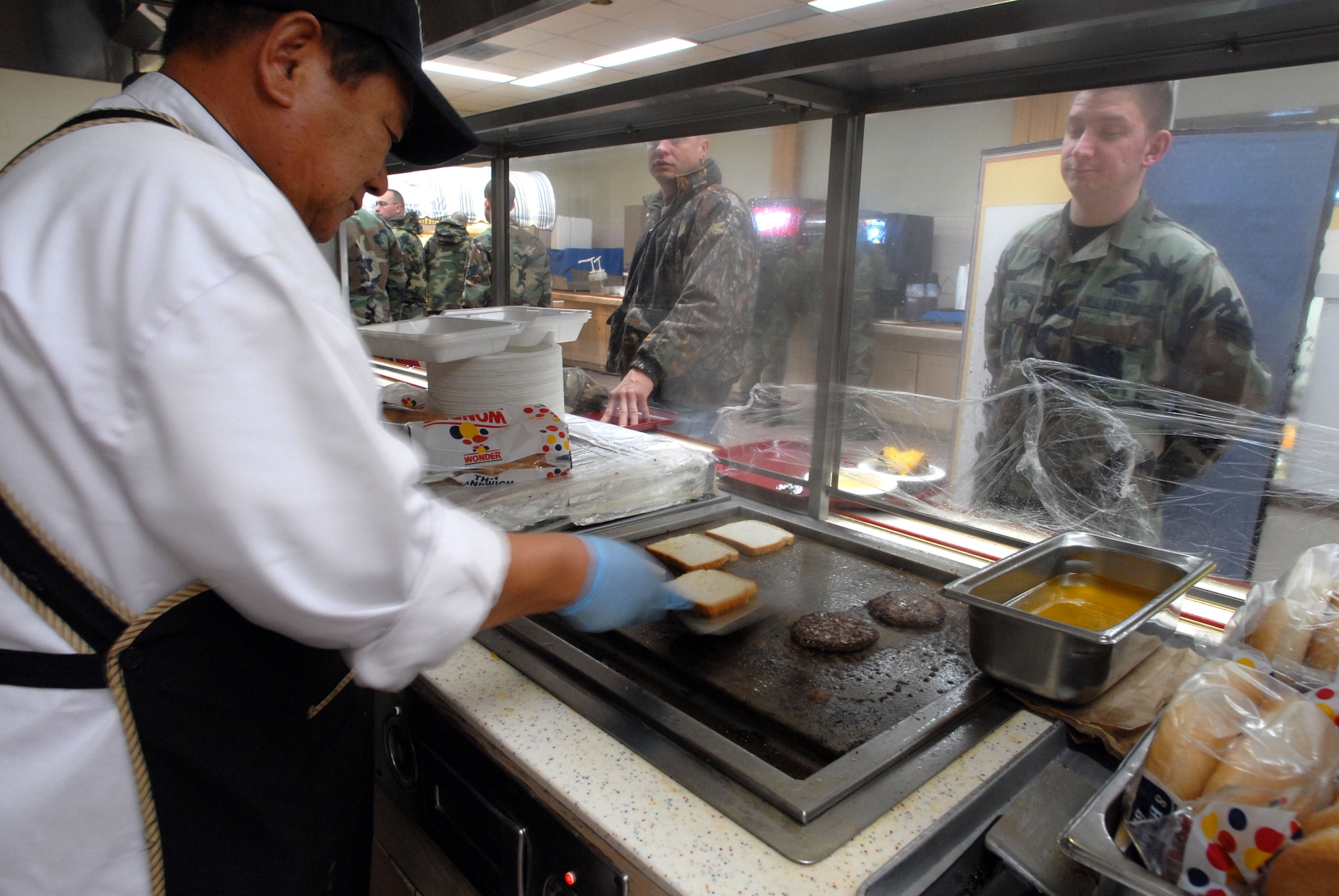 KUNSAN AIR BASE, South Korea -- An employee of Pacific Architect Engineering Korea Limited prepares a hamburger for Senior Airman Bryan Weaver at the O'Malley Dining Facility Jan. 24 here.  The O'Malley Dinging Facility is open for breakfast, lunch, dinner and a midnight meal for about 2,500 Airmen and Soldiers providing them the proper nutrition to remain mission ready. Airmen Weaver is assigned to the 8th Mission Support Group as a client service administrator. (U.S Air Force photo/Senior Airman Steven R. Doty) 