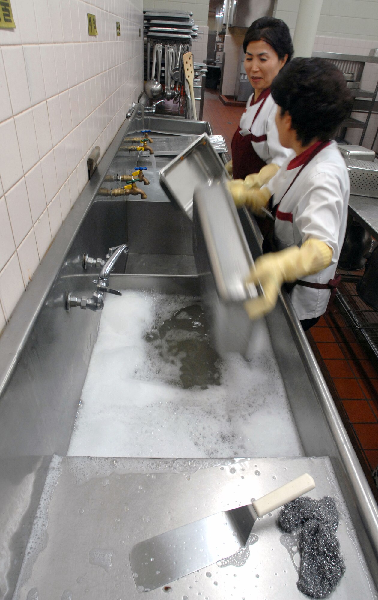 KUNSAN AIR BASE, South Korea -- Employees of Pacific Architect Engineering Korea Limited clean dishes during lunch service at the O'Malley Dining Facility Jan. 24 here.  The O'Malley Dinging Facility is open for breakfast, lunch, dinner and a midnight meal for about 2,500 Airmen and Soldiers providing them the proper nutrition to remain mission ready. (U.S Air Force photo/Senior Airman Steven R. Doty) 
