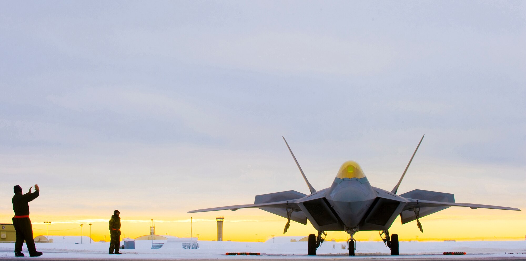 A 90th Aircraft Maintenance Unit crew chief signal an F-22A Raptor laden with concrete bombs to begin its departure for a training mission. For the first time at Elmendorf Air Force Base, Alaska, a mock bomb drop over Alaska, Jan. 16, provides integral training for both fighters and maintainers in preparation to declare its initial operation capabilities. (U.S. Air Force photo/Senior Airman Garrett Hothan)