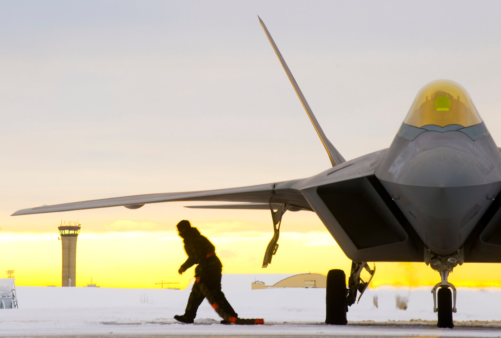 A 90th Aircraft Maintenance Unit crew chief pulls the chocks from an F-22A Raptor laden with concrete bombs before departing for a training mission. For the first time at Elmendorf Air Force Base, Alaska, a mock bomb drop over Alaska, Jan. 16, provides integral training for both fighters and maintainers in preparation to declare its initial operation capabilities. (U.S. Air Force photo/Senior Airman Garrett Hothan)