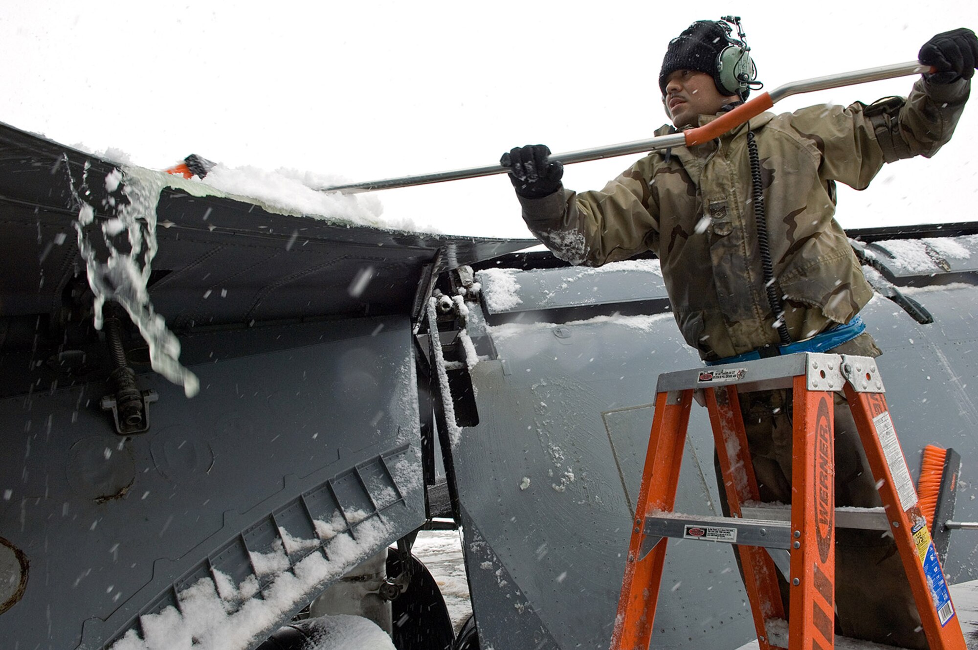 Staff Sgt. Manuel Garibay, sweeps snow from the wing after a recent snow storm. Sergeamt Garibay is deploye to the 376th Expeditionary Aircraft Maintenance Squadron. (U.S. Air Force photo/James West)