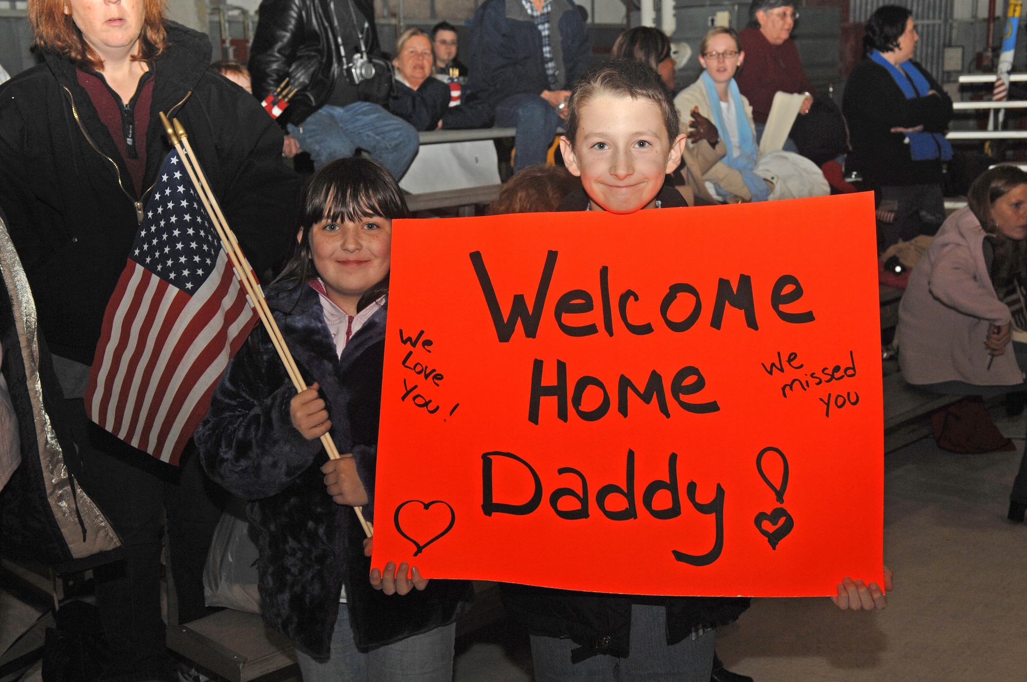 SEYMOUR JOHNSON AIR FORCE BASE, N.C. - Alex Moses(right) and Brandi Moses hold up a sign while waiting for their dad Tracey Moses, from the 336th Aircraft Maintenance Squadron, to return from deployment on 19 January.(U.S. Air Force photo by Senior Airman Jessica Klingler)
