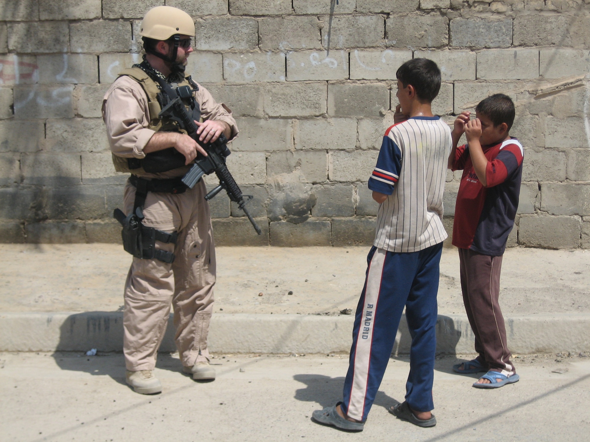 Air Force Office of Special Investigations Special Agent Joshua Goodwin talks to Iraqi children while on patrol in Baghdad. AFOSI agents listen carefully and watch for clues, gathering information that will help them zero in on the insurgents they seek. (U.S. Air Force photo)