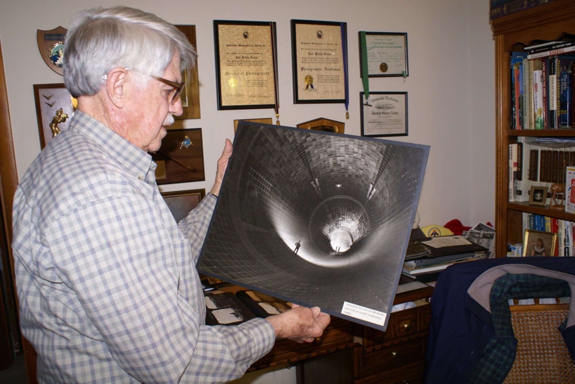 Phil Tarver holds a 16 by 20 inch black and white photographic print of the iconic image seen on AEDC’s Web site of three men, from left, Charlie Powell, in foreground, R. Pierson Smith and Bob Bomar, standing on turning vanes inside AEDC’s 16-foot supersonic wind tunnel test facility. (Photo by Philip Lorenz III)