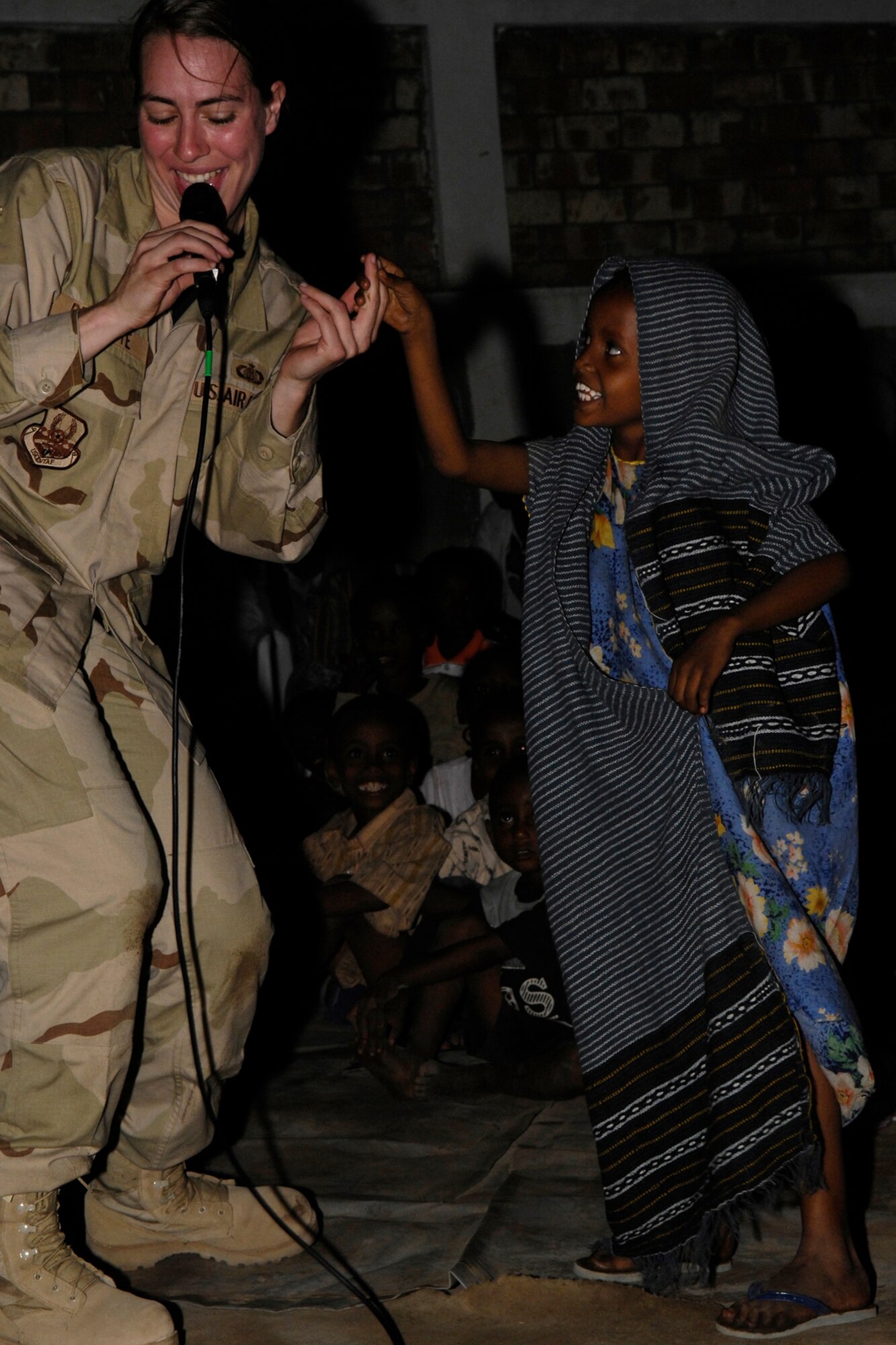 Staff Sgt. Victoria Bruyette, CENTAF Band, Vocalist, dances with a local Djiboutian  girl during a concert held in "Section Six " on January 22, 2008. The CENTAF Band "Live Round" will be performing eight shows in 5 days in Africa for the base and the local community. (U.S. Air Force Photo By: Staff Sgt. Christina M. Styer) 
